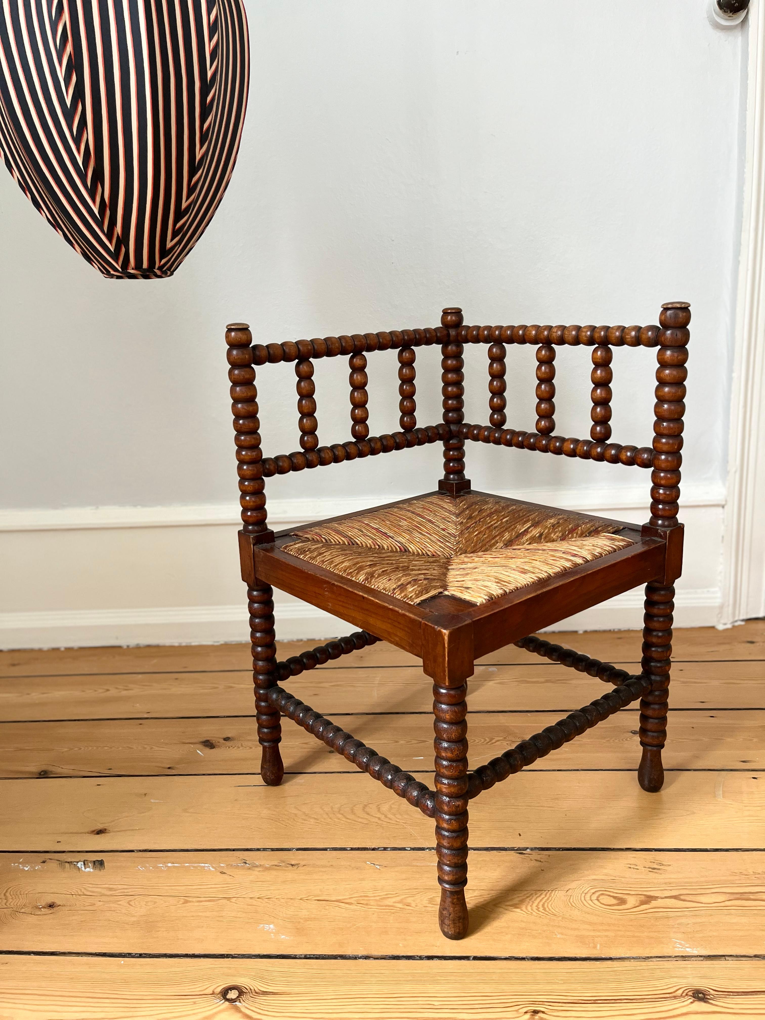 Perfect for a hall or a corner in the dining room. British antique bobbin turned corner chair with a rush seat. Please note that the seat height is lower than a dining chair, more like a lounge chair. 
In very good condition considering it's age,
