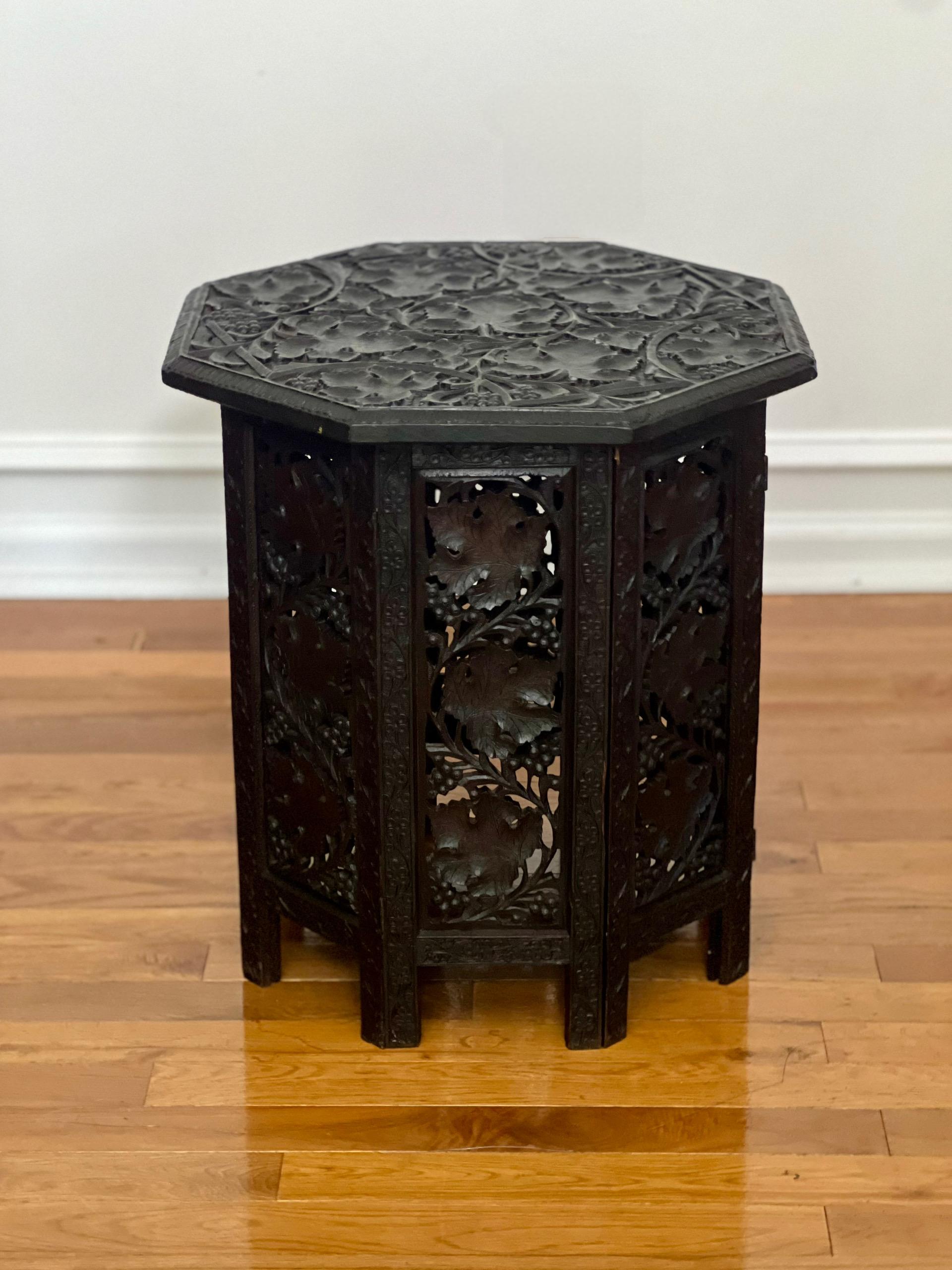 Intricately hand-carved Anglo Indian ebonized folding side table, late 19th-early 20th century.

This is a wonderful work on richly toned hardwood. The collapsible base has eight hinged panels with extensive pierced fretwork of grapevines
