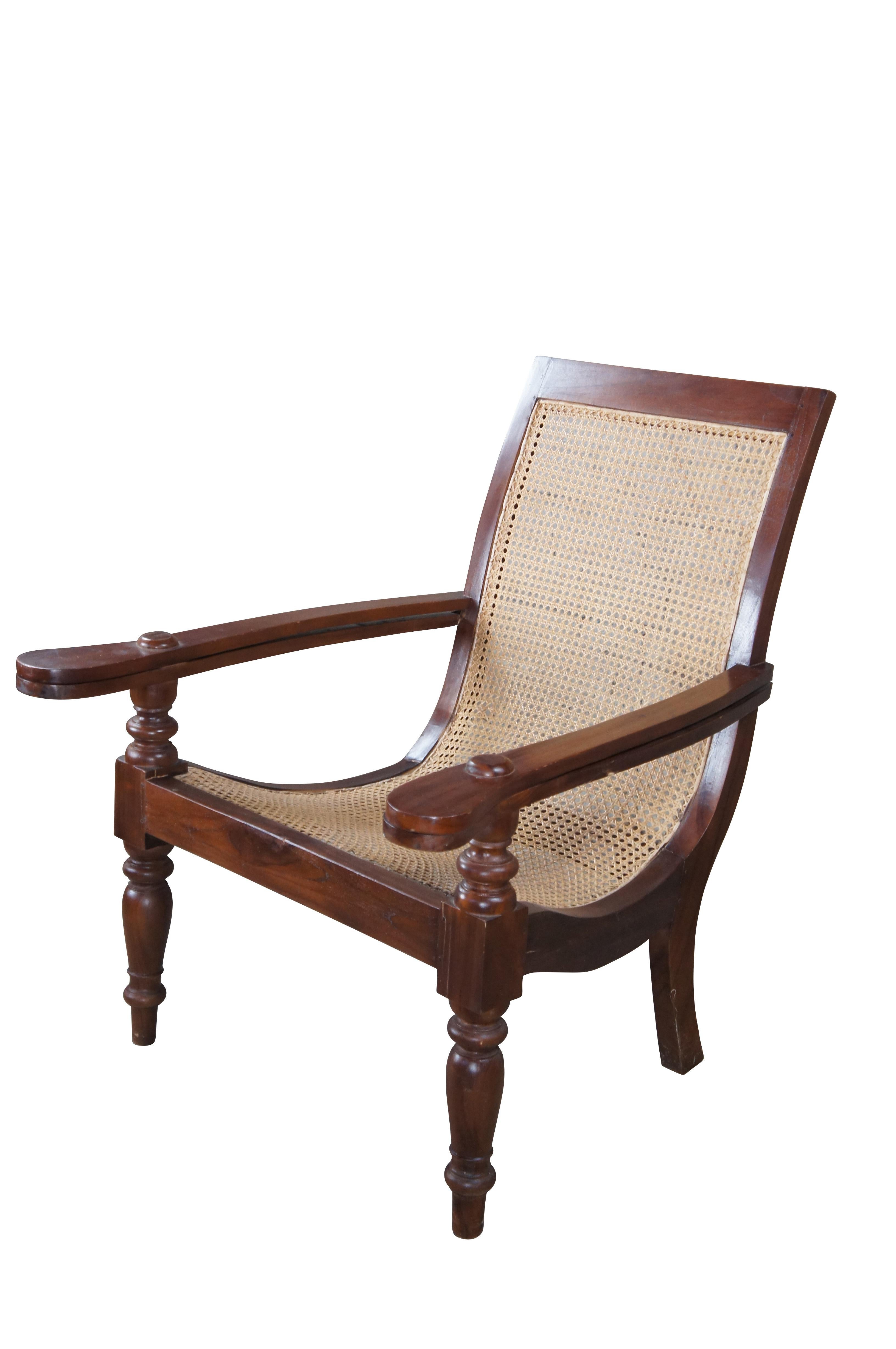 20th century British Colonial Anglo Indian plantation chair. Made from teak in mortise and tenon joinery with a relaxed lounged frame and long extendable arms. Features a relaxed swoop seat with caning throughout. The frame is supported by turned