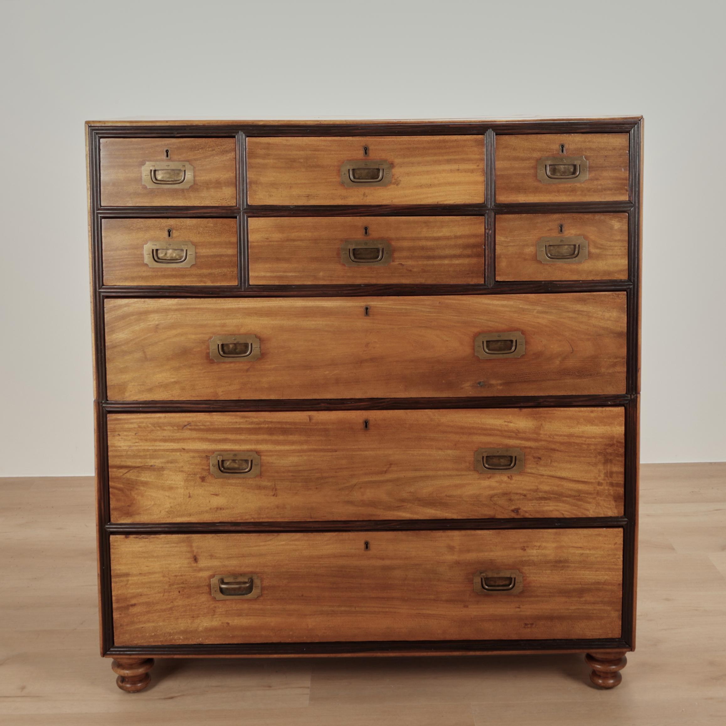 Handsome antique British Colonial campaign chest of drawers crafted in camphor wood in a two piece construction with beaded rosewood trim, brass hardware and turned feet. 