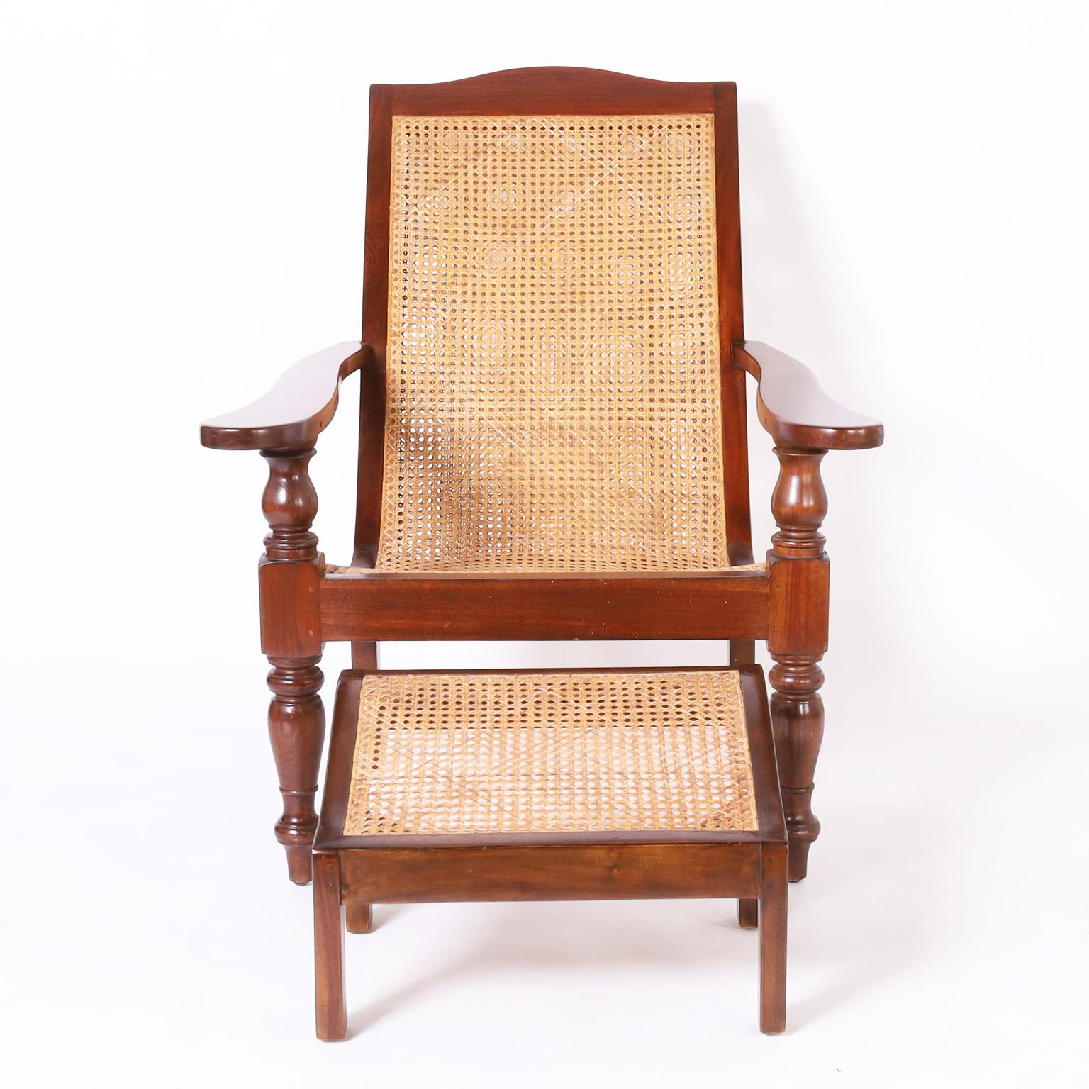 Antique British colonial plantation chair and ottoman hand crafted in mahogany with a pegged construction featuring double caned back, caned seat and ottoman, classic elegant form, and turned front supports and legs.

Ottoman measures H: 13 W: 20