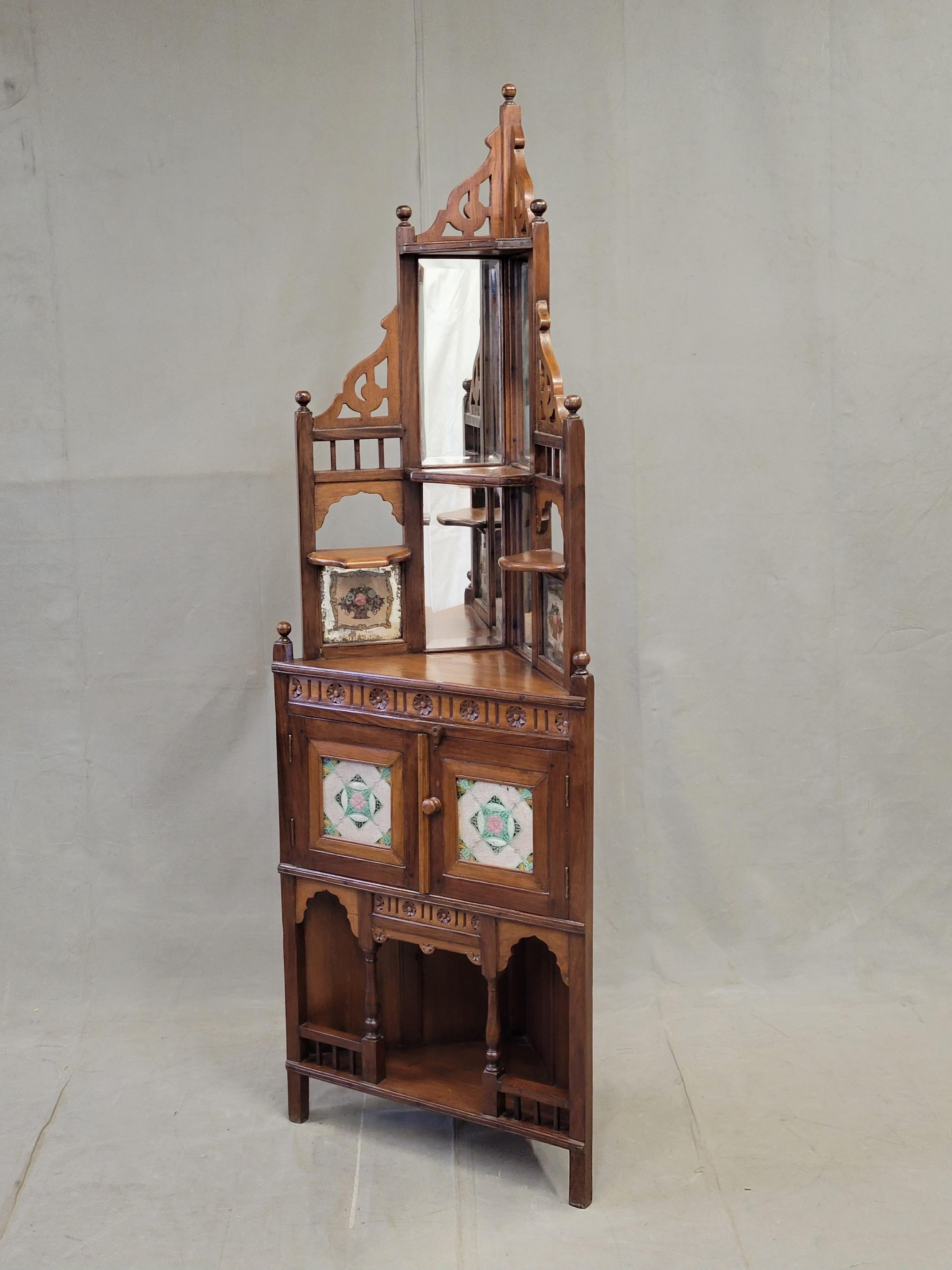 Charmant meuble d'angle ancien en teck, datant de 1930, de style Charme Antiques (Indien). La partie centrale supérieure est dotée d'un miroir tandis que des carreaux de verre peints représentant des paniers de fleurs encadrent la partie en miroir