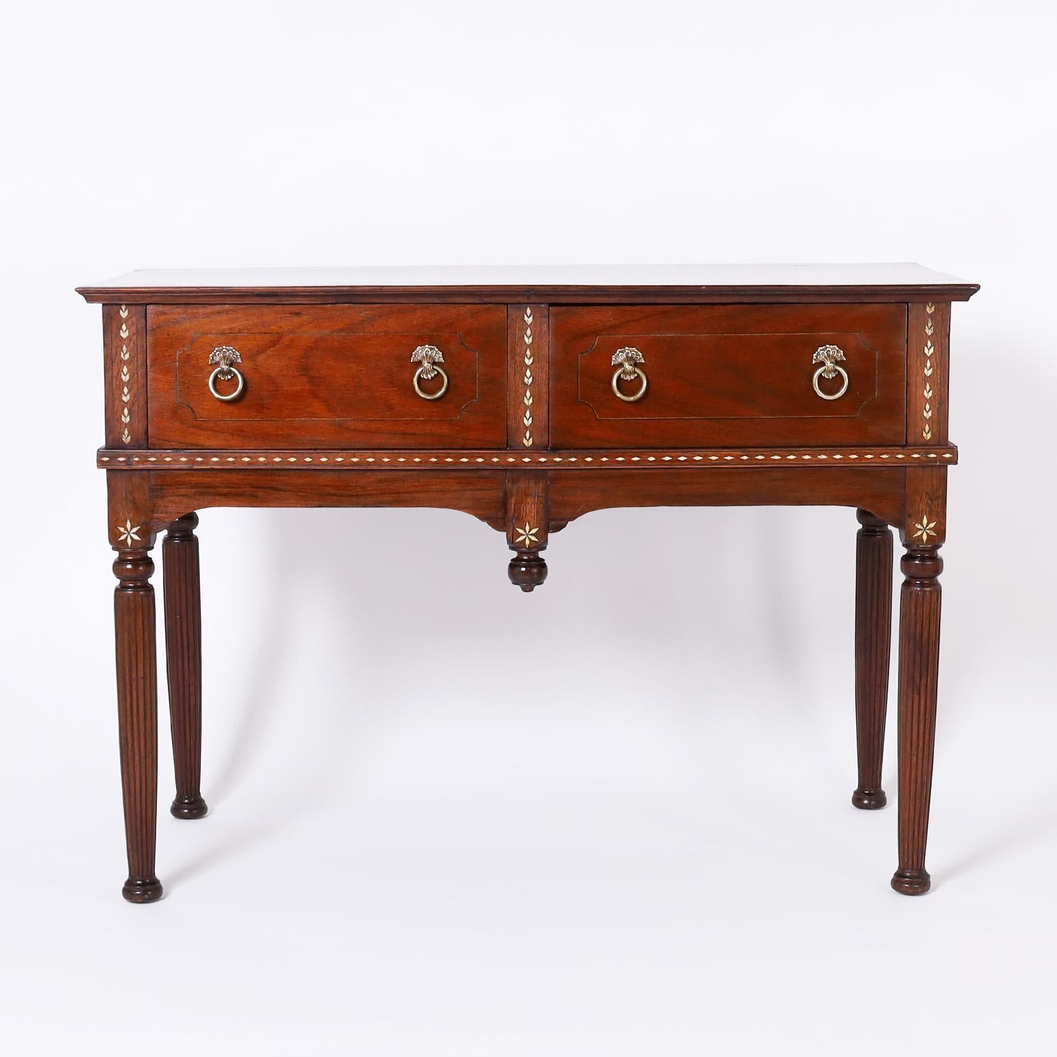 Rare and remarkable 19th century British colonial two drawer server from the Philippines, handcrafted in mahogany with a lush grain, featuring pegged construction, brass hardware, seashell inlays and elegant turned and beaded legs.