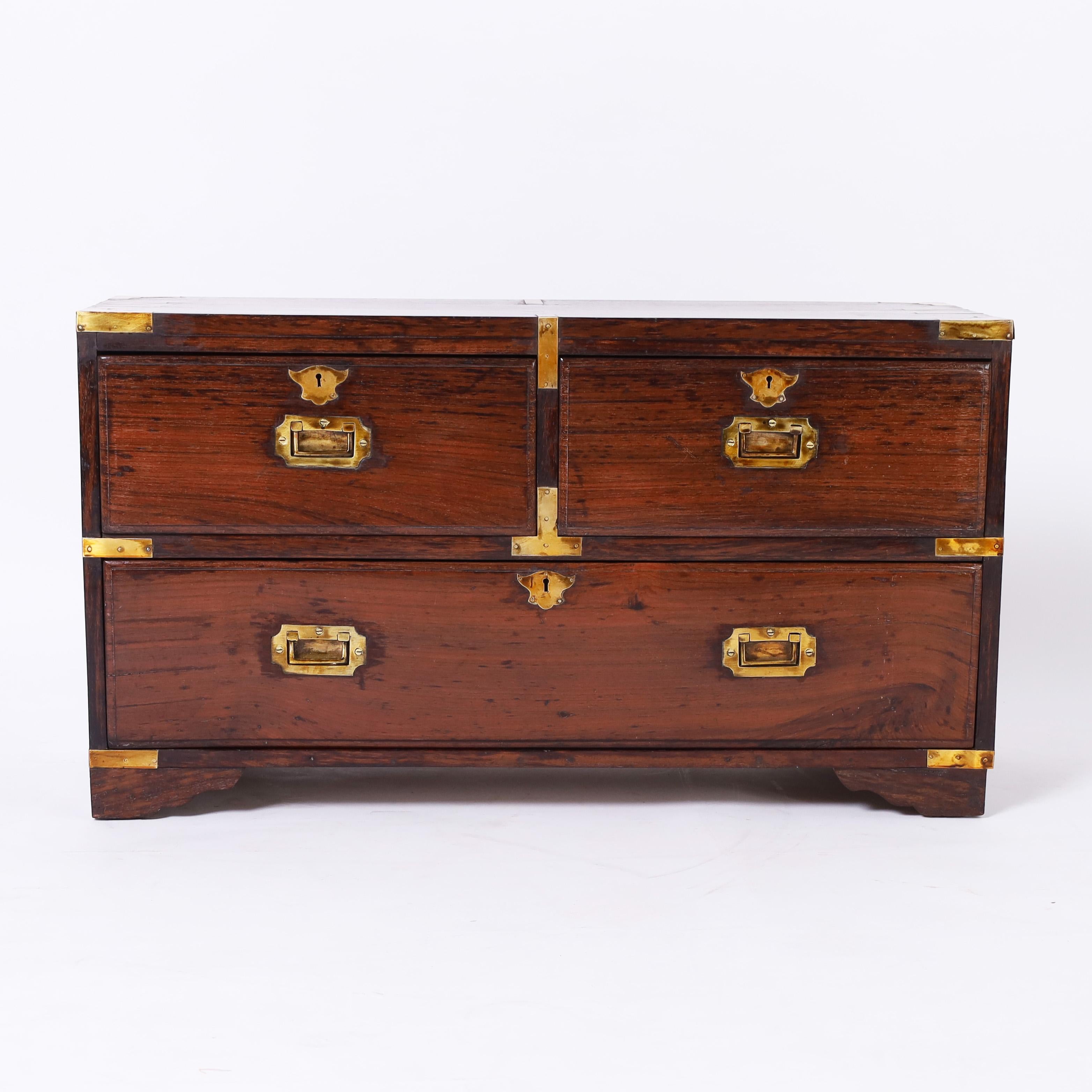 Handsome 19th century English campaign chest handcrafted with rosewood in an unusual form with three drawers, brass hardware, and bracket feet.