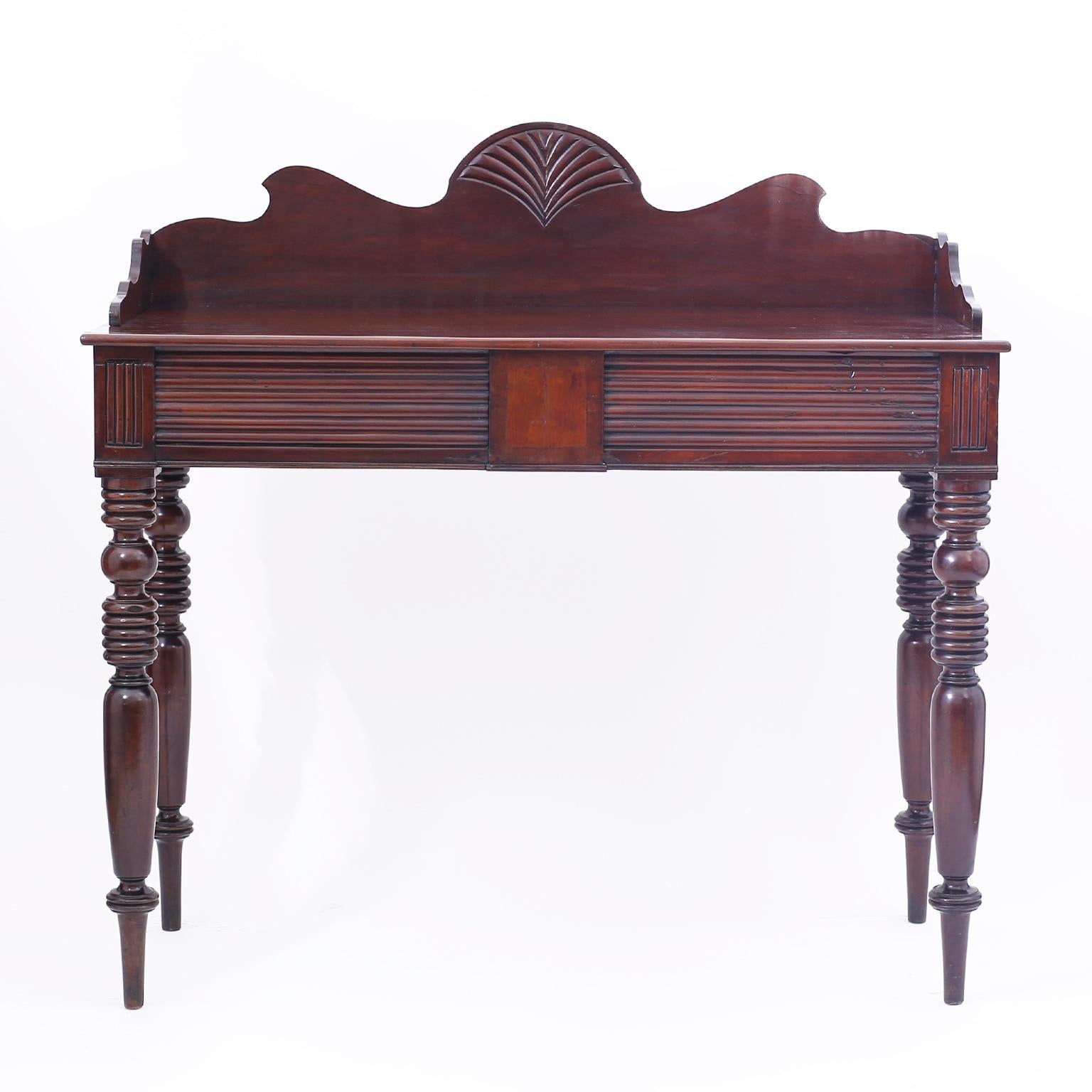 Impressive West Indies server from Jamaica handcrafted in indigenous lush grained mahogany featuring the proverbial dramatic carved and scalloped gallery, a hidden storage drawer on one side and long elegant turned legs.