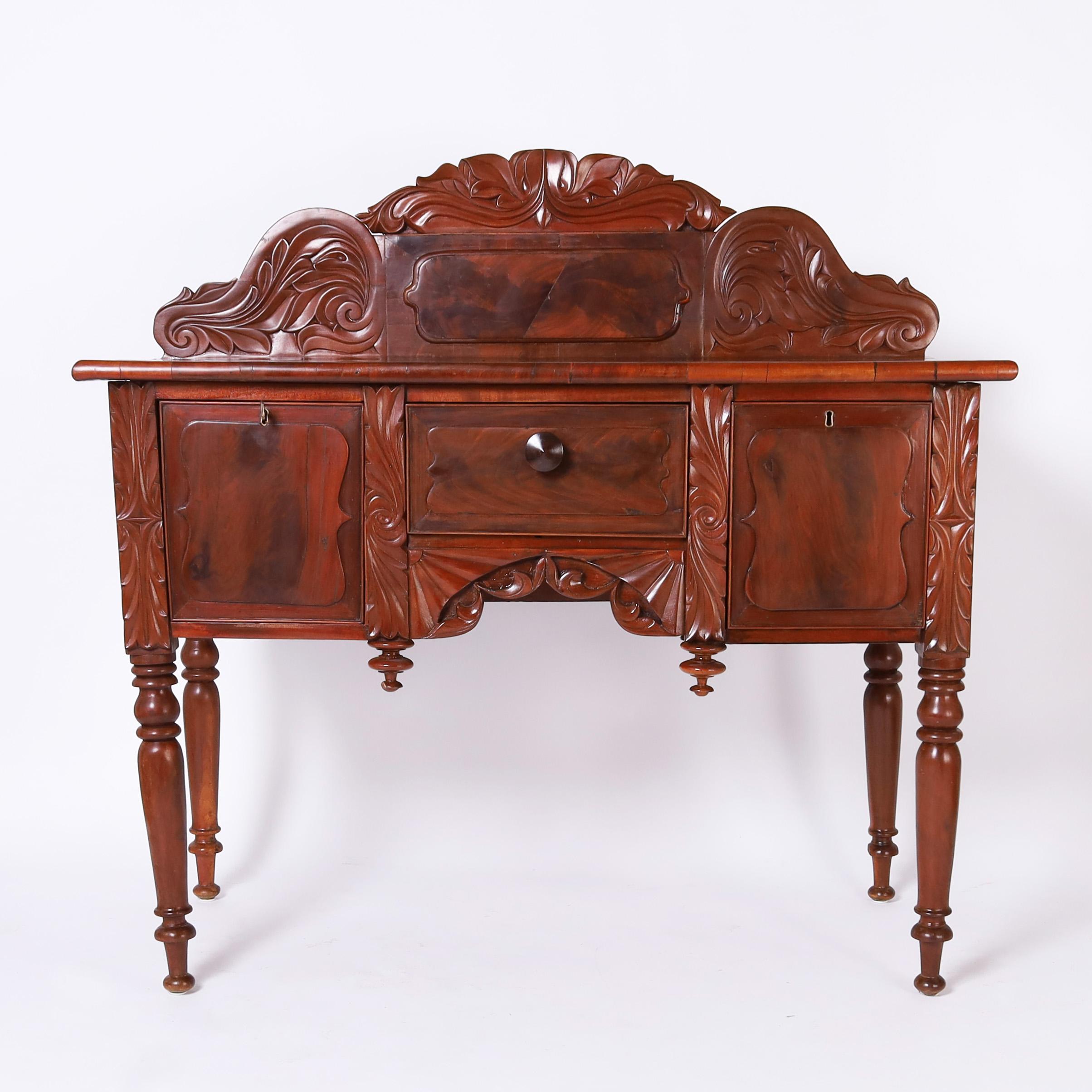 Splendida credenza coloniale britannica del XIX secolo realizzata a mano in mogano e caratterizzata da un'imponente schienale con intagli ispirati all'oceano su una cassa con tre cassetti, foglie d'acanto intagliate, ventagli intagliati, terminali e