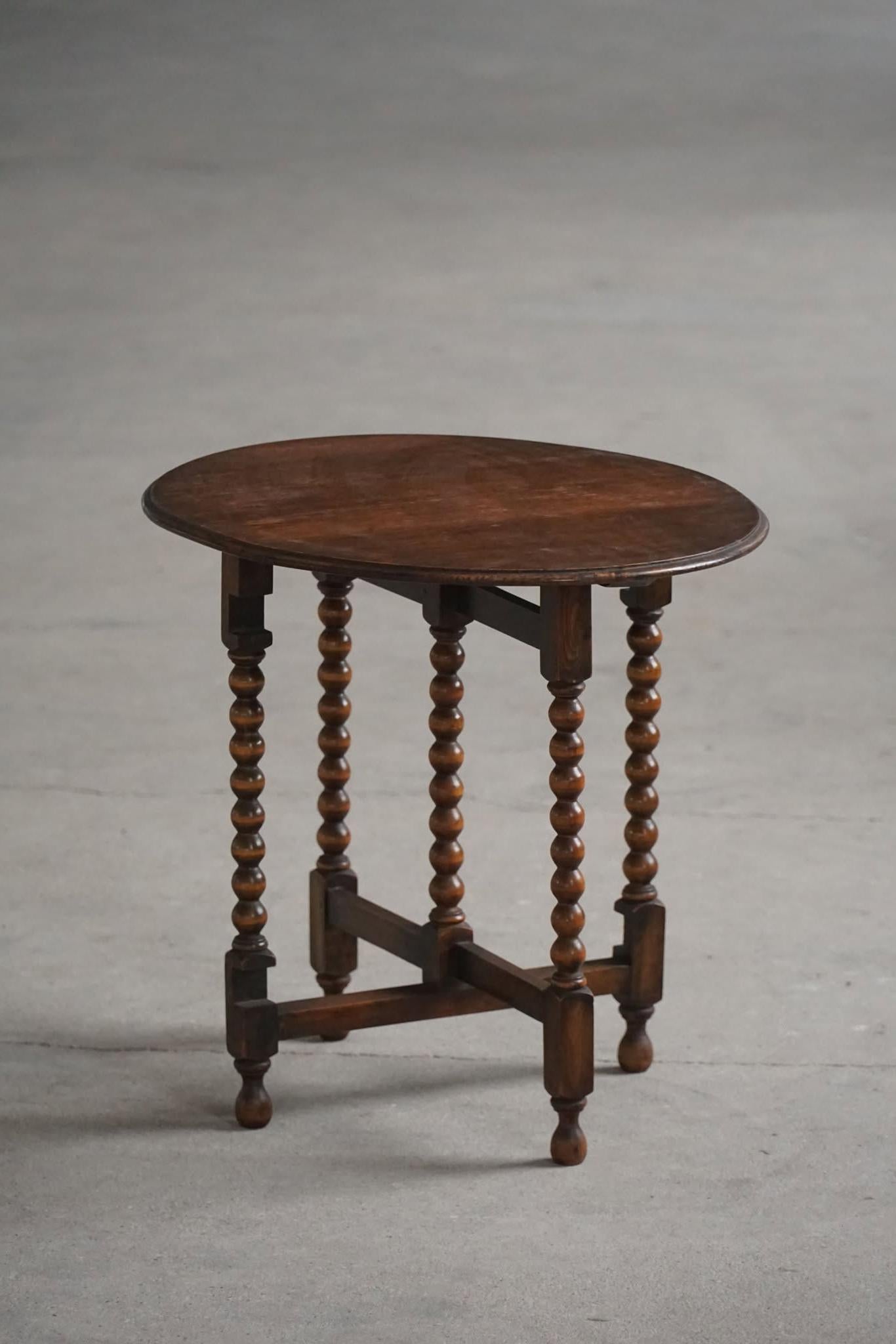 A beautiful romantic antique English drop leaf side table in solid oak with nice carved bobbin legs. Dated back to 1890-1910. The overall condition is good, showing some natural signs of wear. A lovely object for the modern interior. This item also