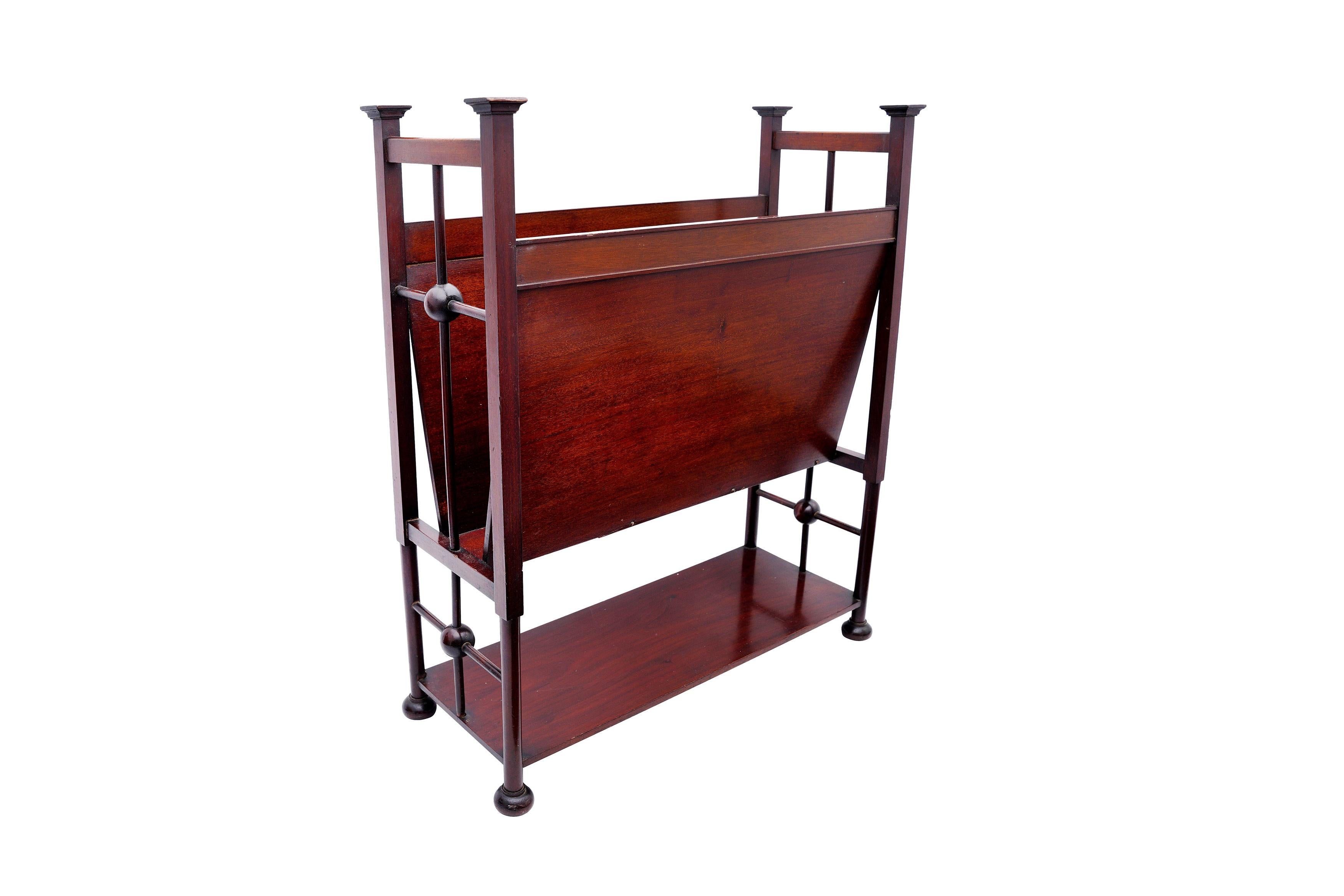 Liberty's of London An Elegant  Arts & Crafts Magazine / Newspaper Rack, early 20th century, mahogany, the central 'V' section magazine rack over under tier shelf, within spindle and ball-joint framework end sections, and raised on compressed bun