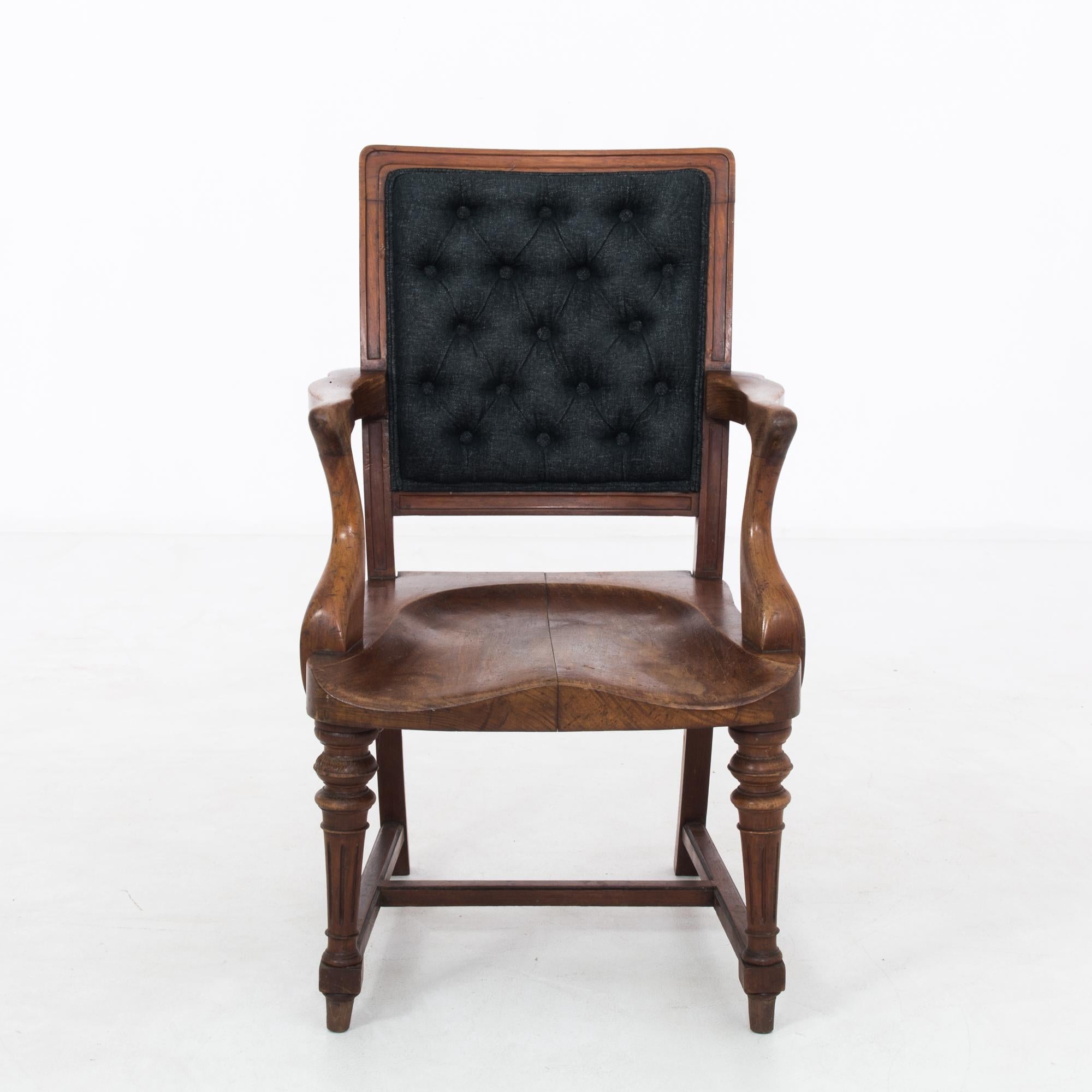 An antique wooden armchair with upholstered back from the United Kingdom, produced circa 1900. A piece clearly influenced by the popular Art Nouveau style that spread across the globe at the turn of the twentieth century, seen in the muted whiplash