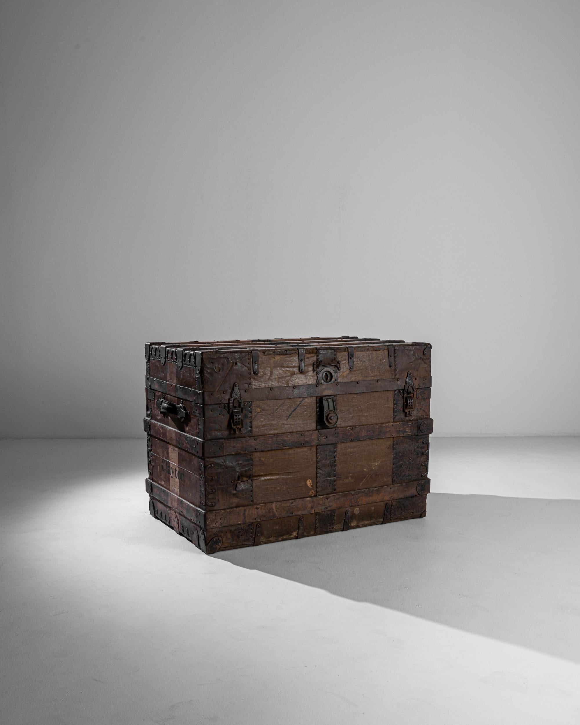 Ce robuste coffre en bois a été fabriqué au Royaume-Uni vers 1900. Le coffre est renforcé par des feuilles de fer, les côtés et les ceintures par des lattes de bois pour une durabilité accrue. Des éléments en fer ornemental - boulons de traction,