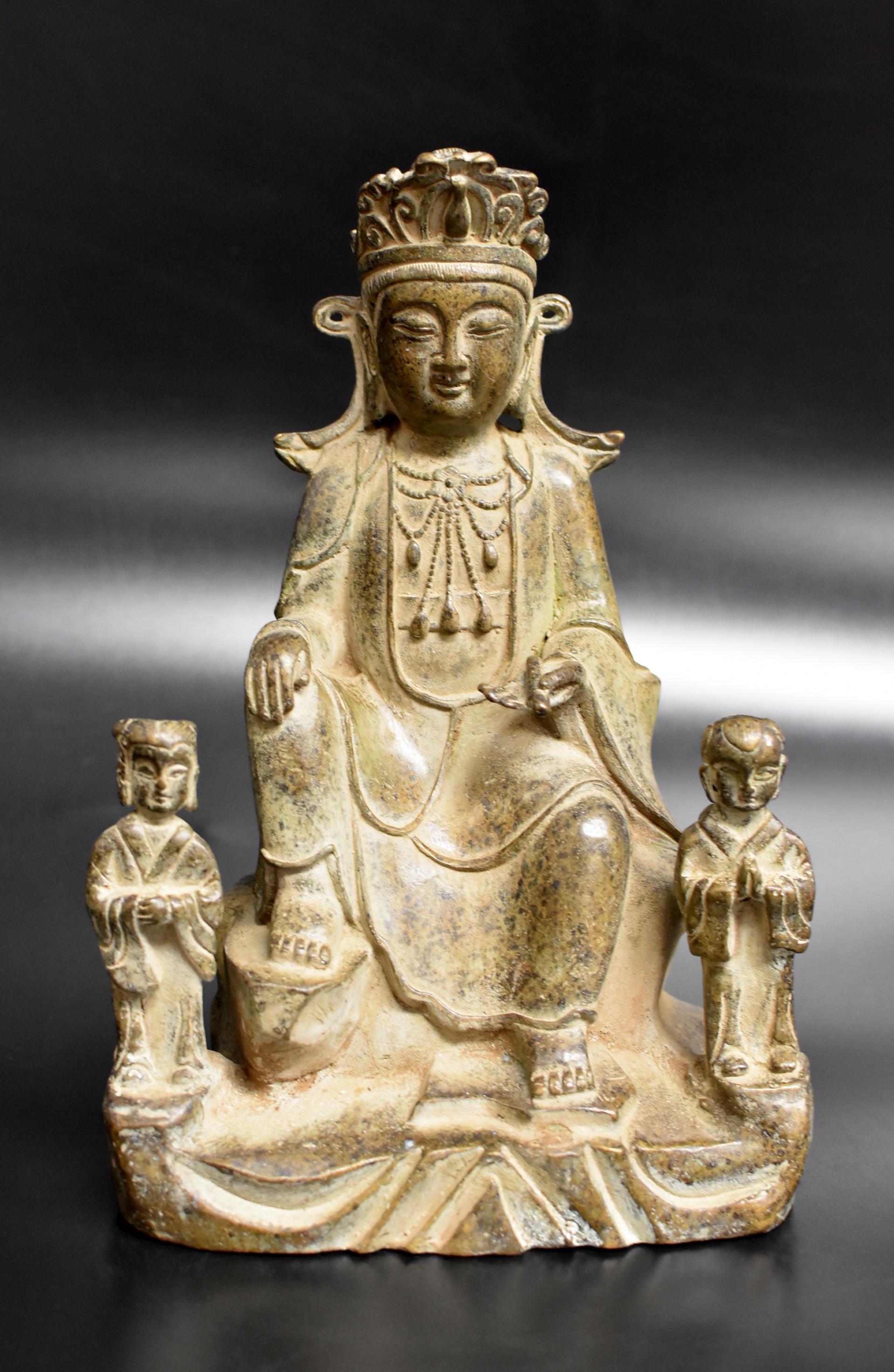 A beautiful antique bronze statue of Buddha as teacher. Seated in rajalilasana (royal ease) on a rock, the hands in bhumisparsha mudra holding a scroll of scripts, wearing a flowing robe draping over the shoulders, revealing a long multi-layered