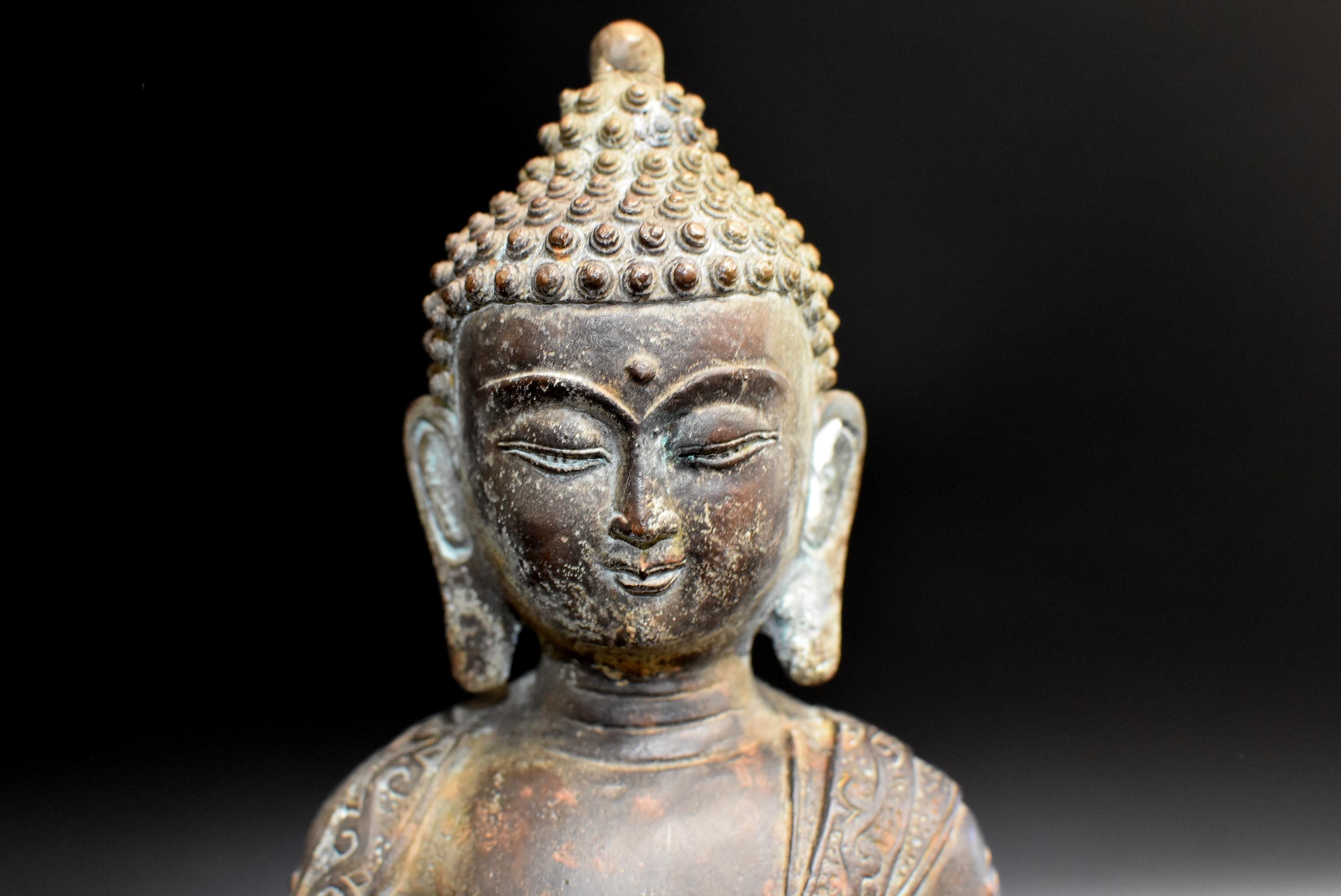 Exceptional Value! A beautiful, large bronze statue of a Buddha. Buddha is seated on a lotus throne and is wearing an elaborately decorated robe with motifs of clouds, dragons, foliage and scrolls. A Tang dynasty style full face, refine facial