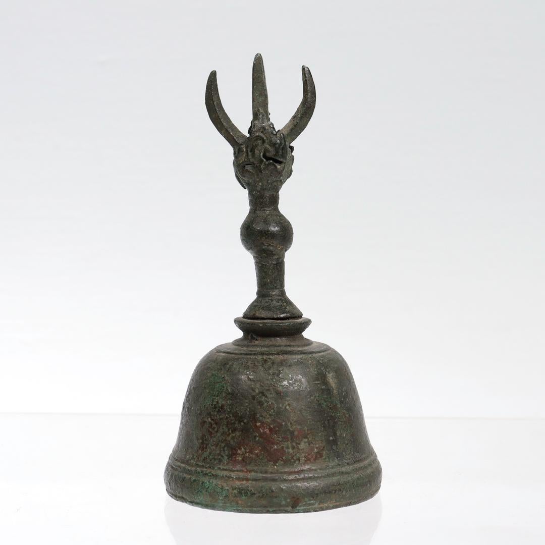 A fine antique bronze ghanta bell.

Likely of Tibetan or Japanese origin.

In the form of a curved bell with a vajra style handle. 

Bell and vajra are a ritual instrument pair in many Buddhist traditions. The ringing of the bell is auspicious and