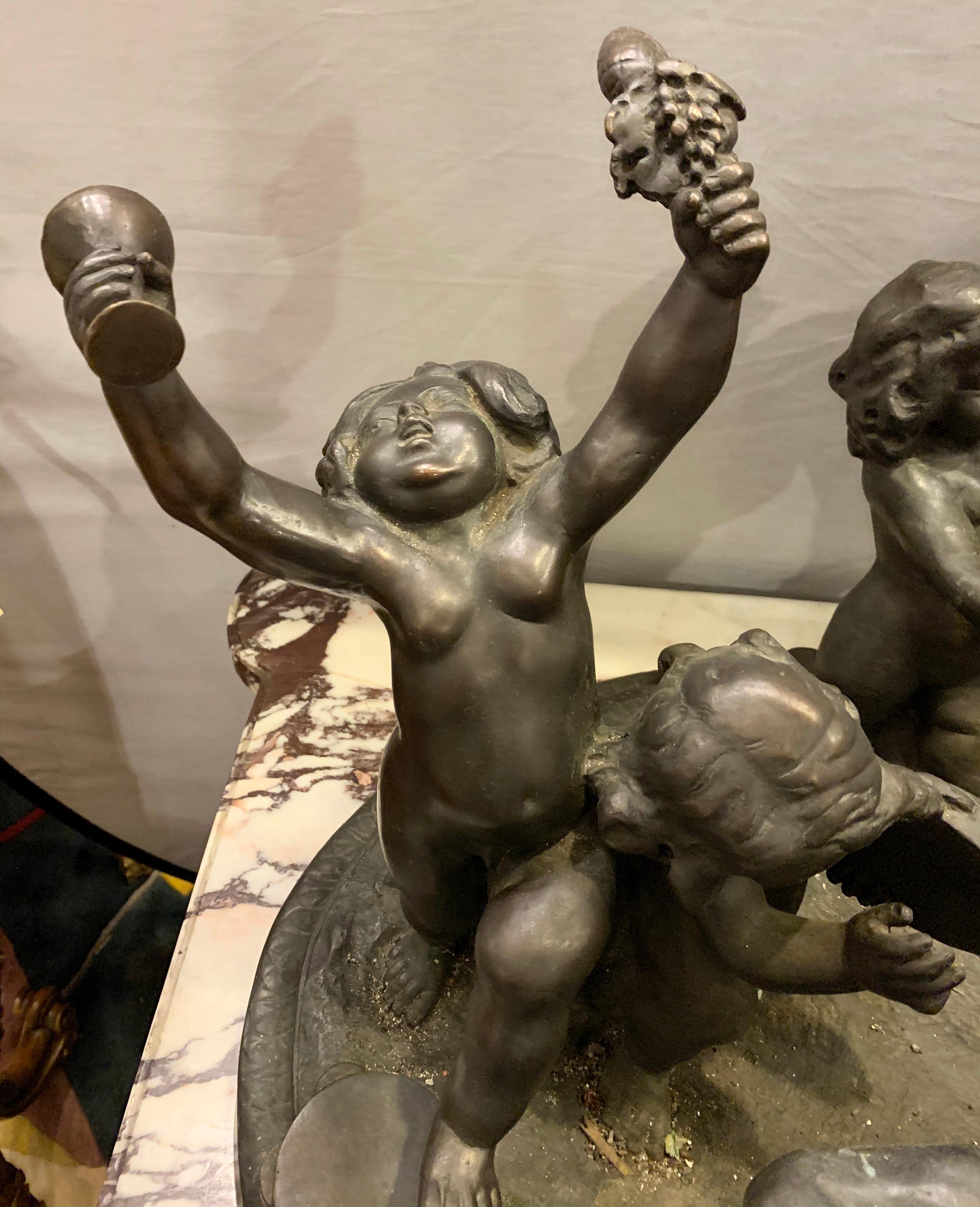 Antique bronze cherub group sculpture or centerpiece of drunken playing cherubs. This simply delightful grouping is large and impressive as it sits almost four feet wide and depicts many drunken cherubs playing on their donkeys and petting their