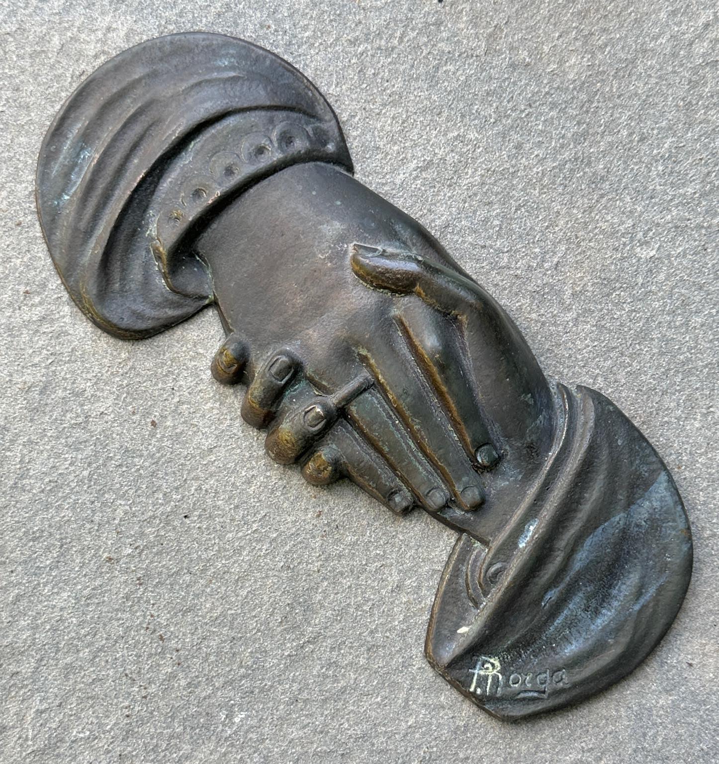 Cast bronze clasped hands by Sylvain Norga. Belgium circa 1915. Norga was known for his religious themed castings. This piece would have been mounted to an object or structure. Extreme good condition with its untouched original surface. It measures