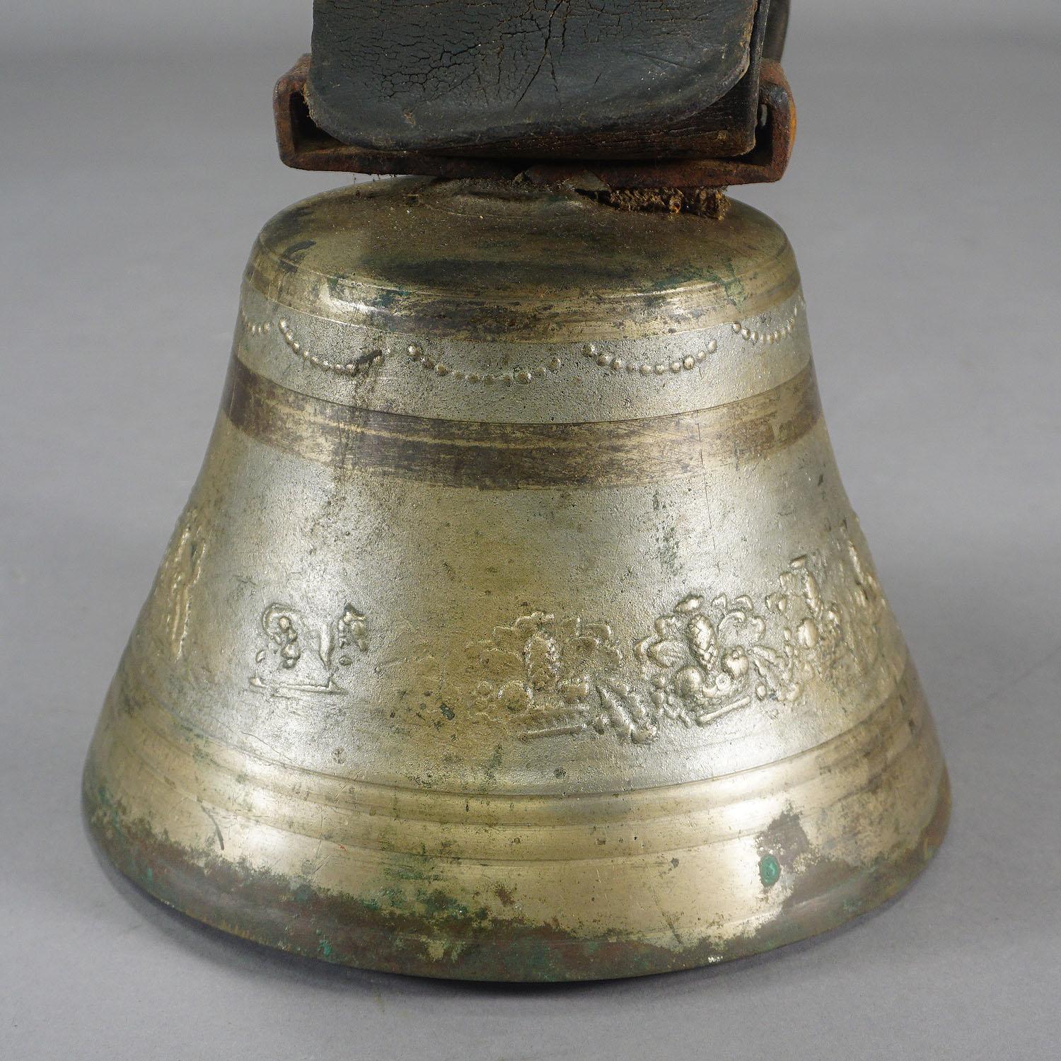 A large casted bronze cow bell manufactured in Switzerland, around 1900. The antique bell features high relief motifs of fruits and foliages. The bell comes with its original brown leather strap with buckle. Bells like this one are still used