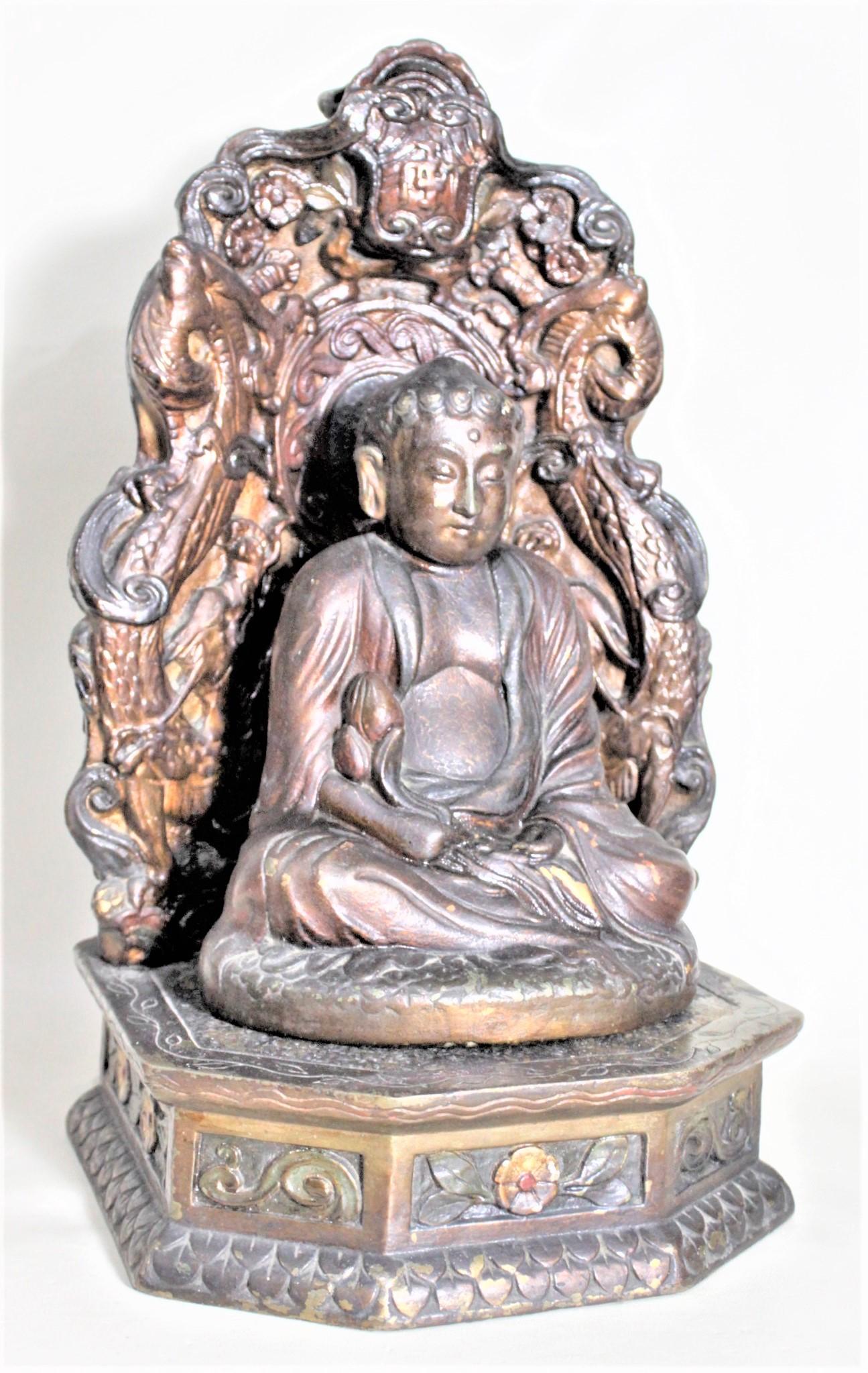 Cette sculpture antique de Bouddha en bronze moulé et trempé et son support sont signés par un fabricant inconnu, et on suppose qu'ils ont été fabriqués en Chine vers 1920. Le support orné et la sculpture du Bouddha sont tous deux composés d'un