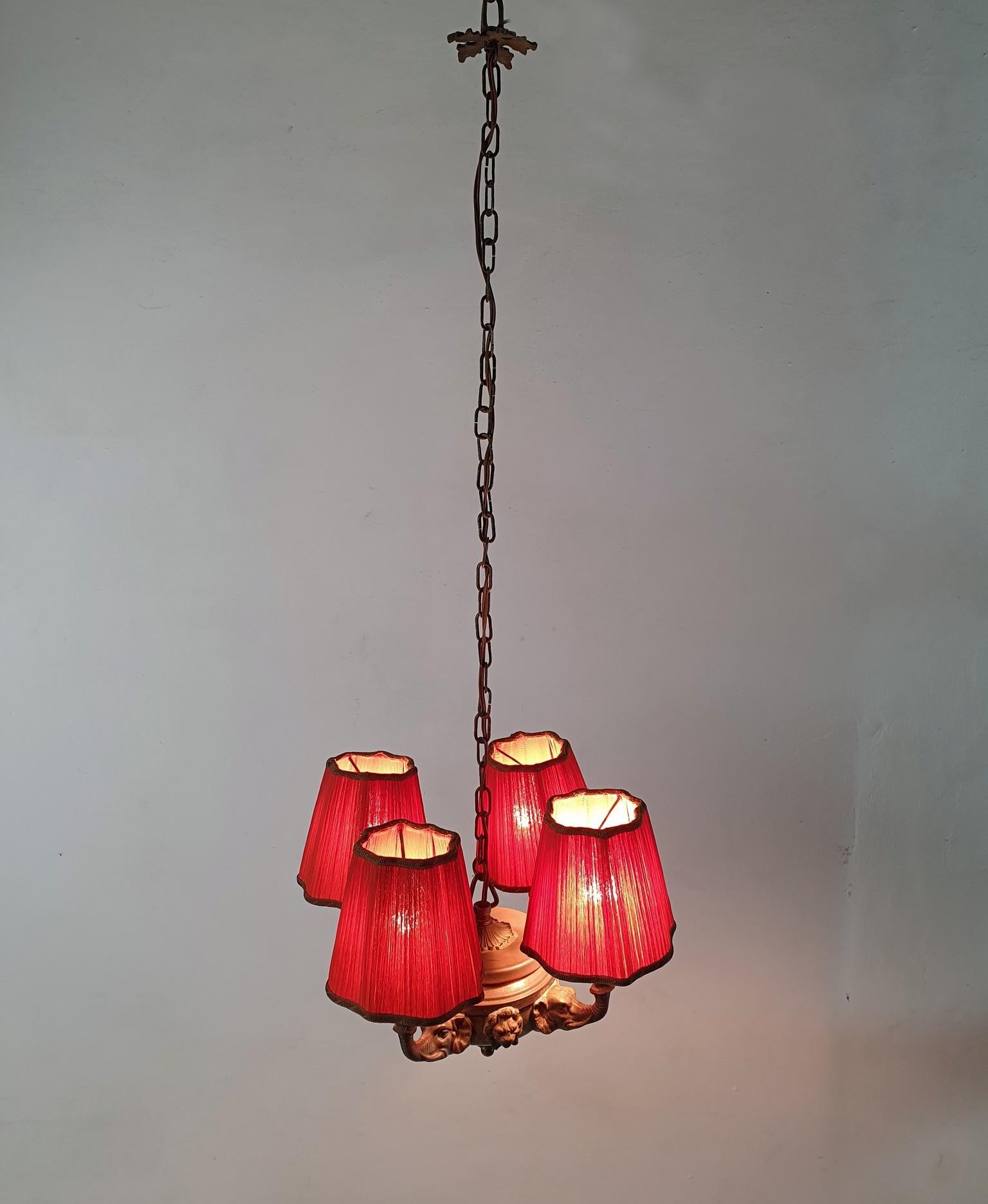 Ce pendentif est tout simplement unique et charmant. Produit en France vers l'année 1900. Il est composé de quatre bras en forme de têtes d'éléphants qui soutiennent chacun une ampoule et sont couronnés d'abat-jour vintage en organza orange. Vendu