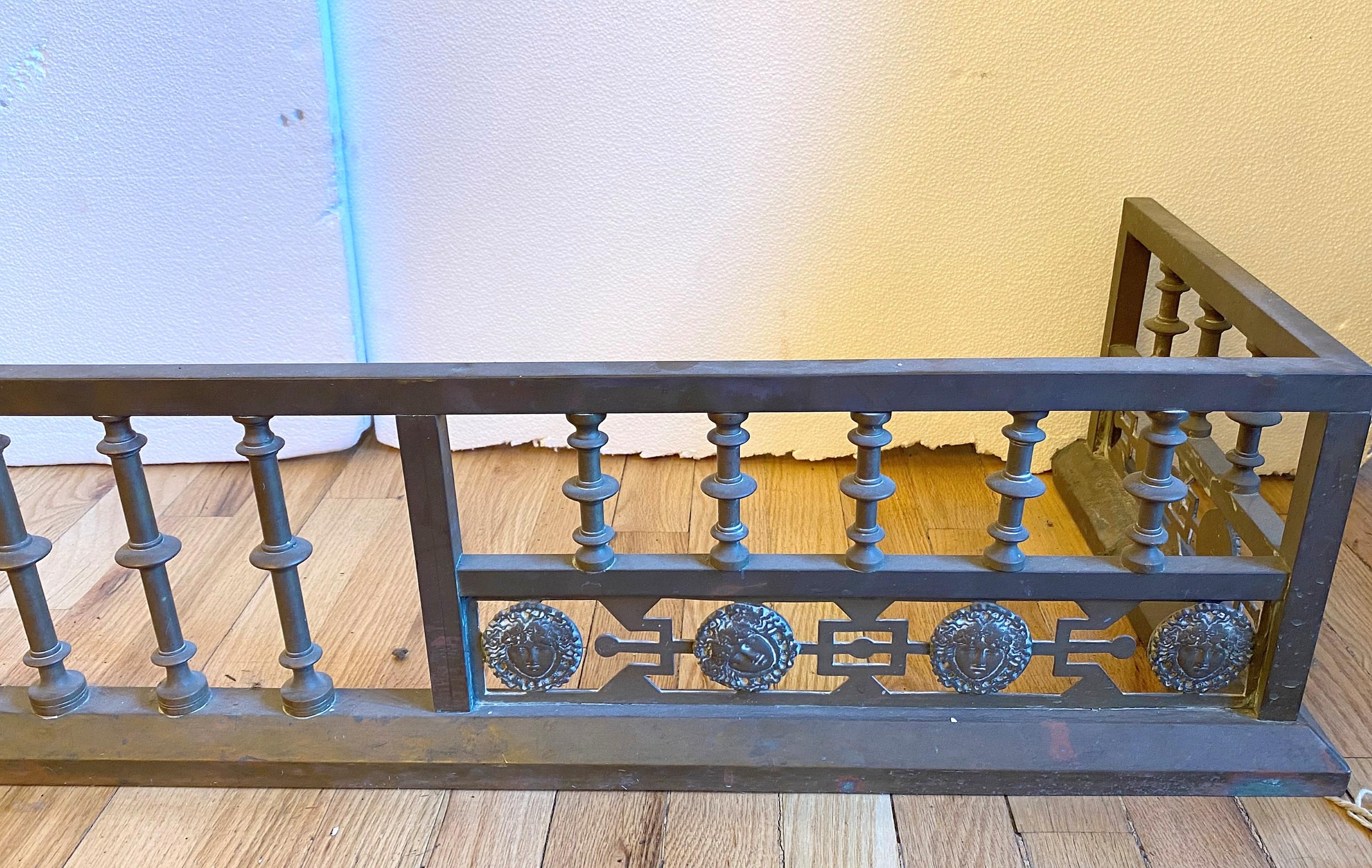 Early 20th century bronze fireplace fender. Features ornate sun faces around the bottom. Geometric design. Please note, this item is located in one of our NYC locations.