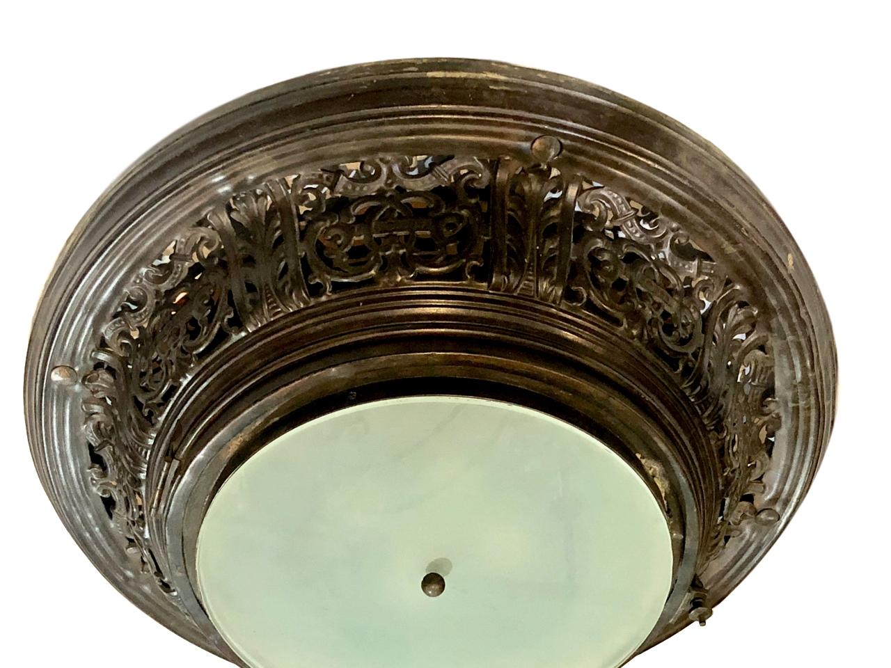 A circa 1910 French semi-flush antique bronze pierced light fixture with frosted glass inset.

Measurements:
Diameter 27