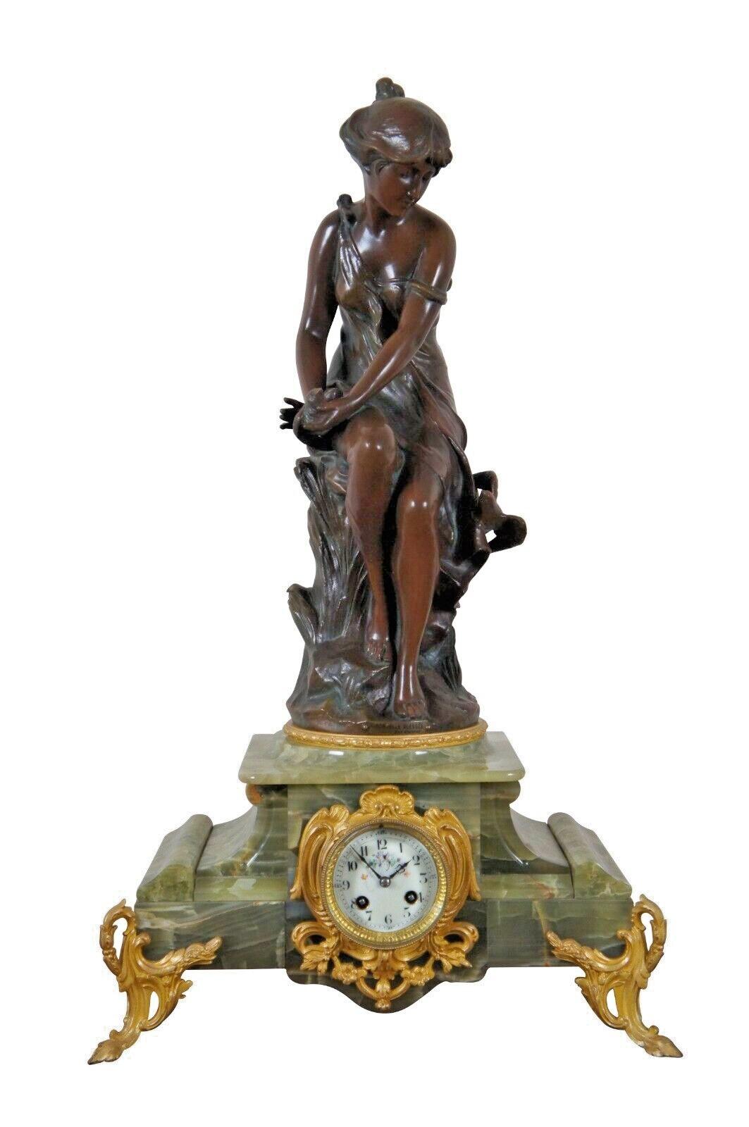 Antique three piece set garniture clock made of bronze with green marble bases and gilt feet. Mantel clock features the sculpture Hirondelle Blessee by Alfred Jean Foretay above a gilt framed, white porcelain clock face with hand painted florals and