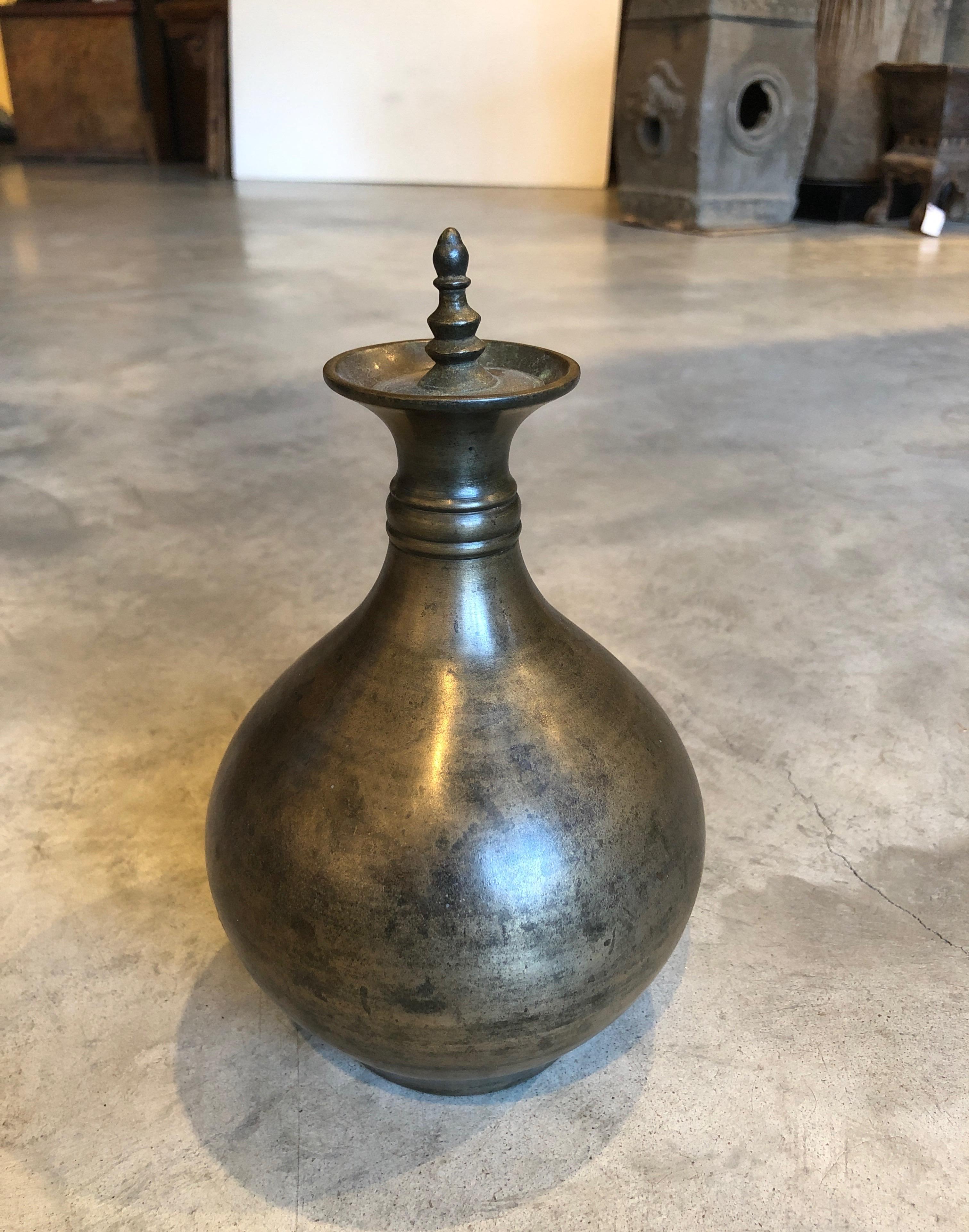 A graceful, well cast and simply designed bronze holy water container. From India, circa 1900 or earlier, this piece will add interest and beauty to any table or shelf. This kind of piece was used daily in rituals, often in a temple setting. The