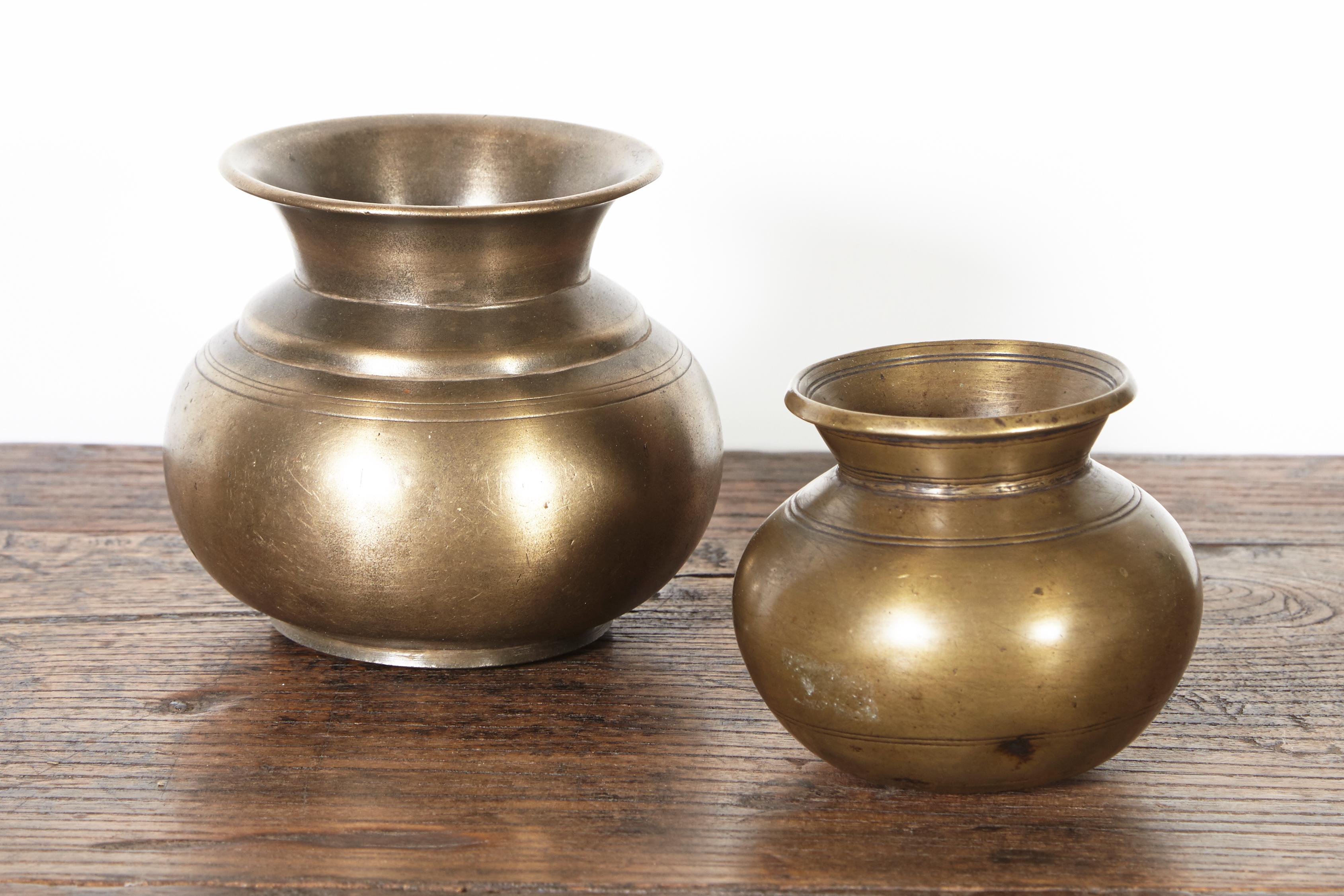 Two beautifully shaped and patinated antique bronze holy water vessels from Nepal, each one with attractive and subtle detail. These ceremonial objects show their decades of loving use. They are spiritual and handsome pieces. Priced and sold