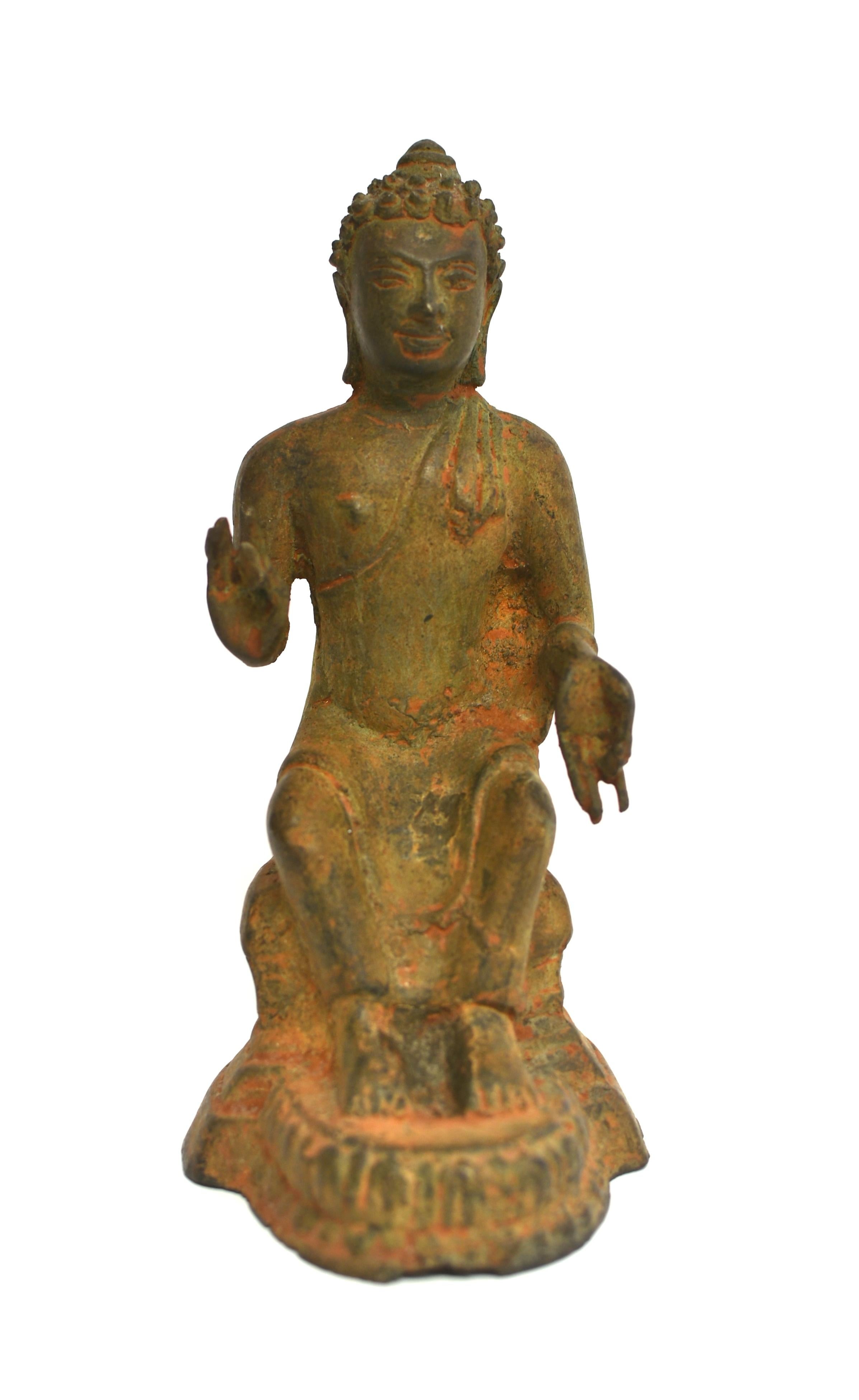 An antique Indian Buddha statue in all original condition. The face with straight sharp nose, full lips under large eyes. An urna between the brows symbolizing the third eye to decipher and conquer evil, under coiled hair gathered into a chignon.