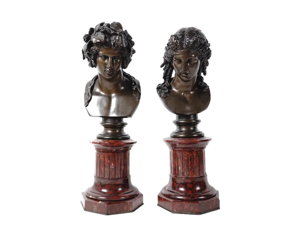 A pair of antique bronze busts after Ferdinand Barbedienne, French, 1810 to 1892. The patinated bronze busts depict Greek god Bacchus and the Greek goddess Ariadne. Each bronze sculpture stands on a matching rouge marble plinth column base pedestal.