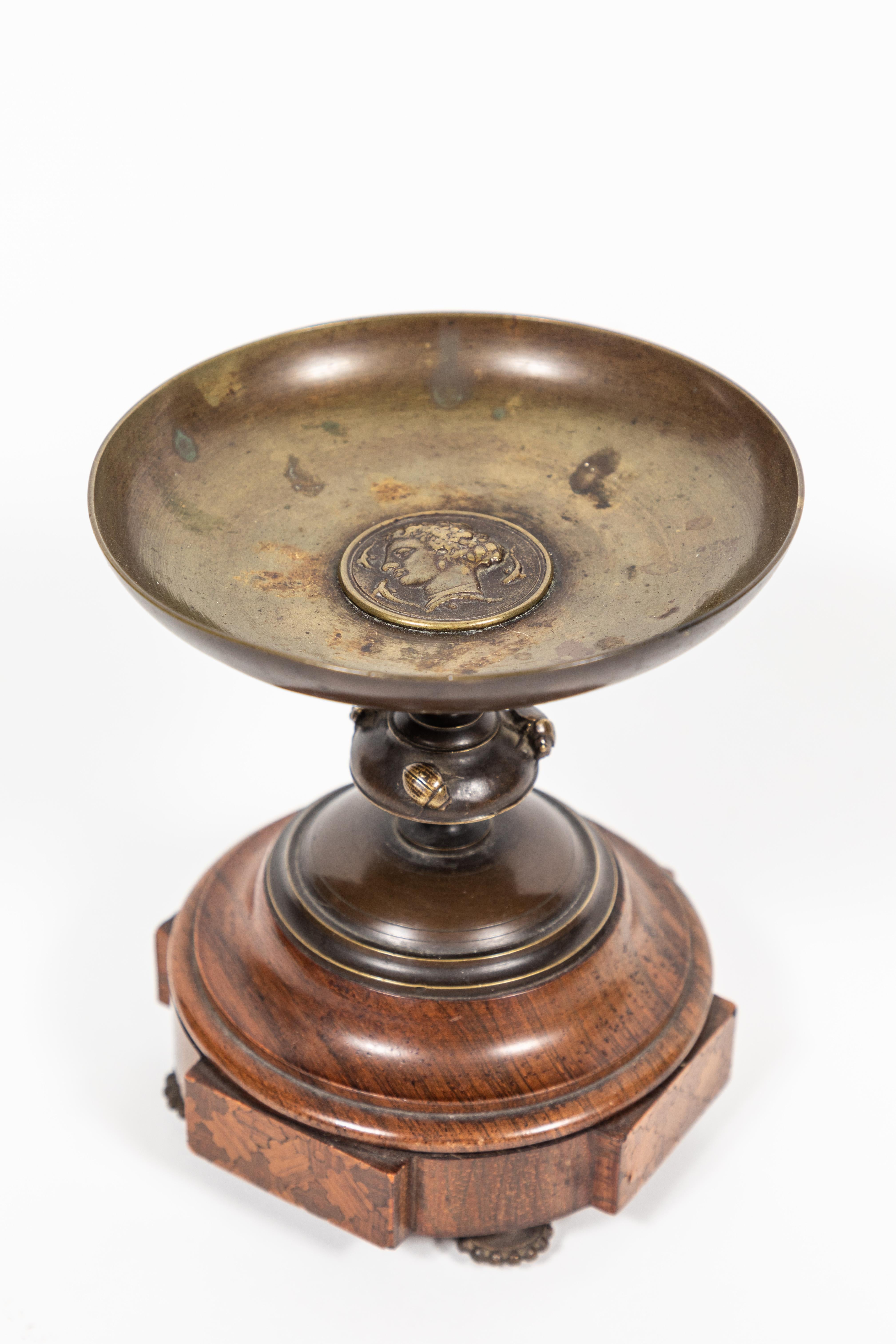 Antique bronze pedestal dish with Greco-Roman medallion of man's head. Second tier is adorned by 3 Scarabs. The beautifully grained wood base has 4 intricate marquetry panels and is finished off by decorative beaded metal feet.