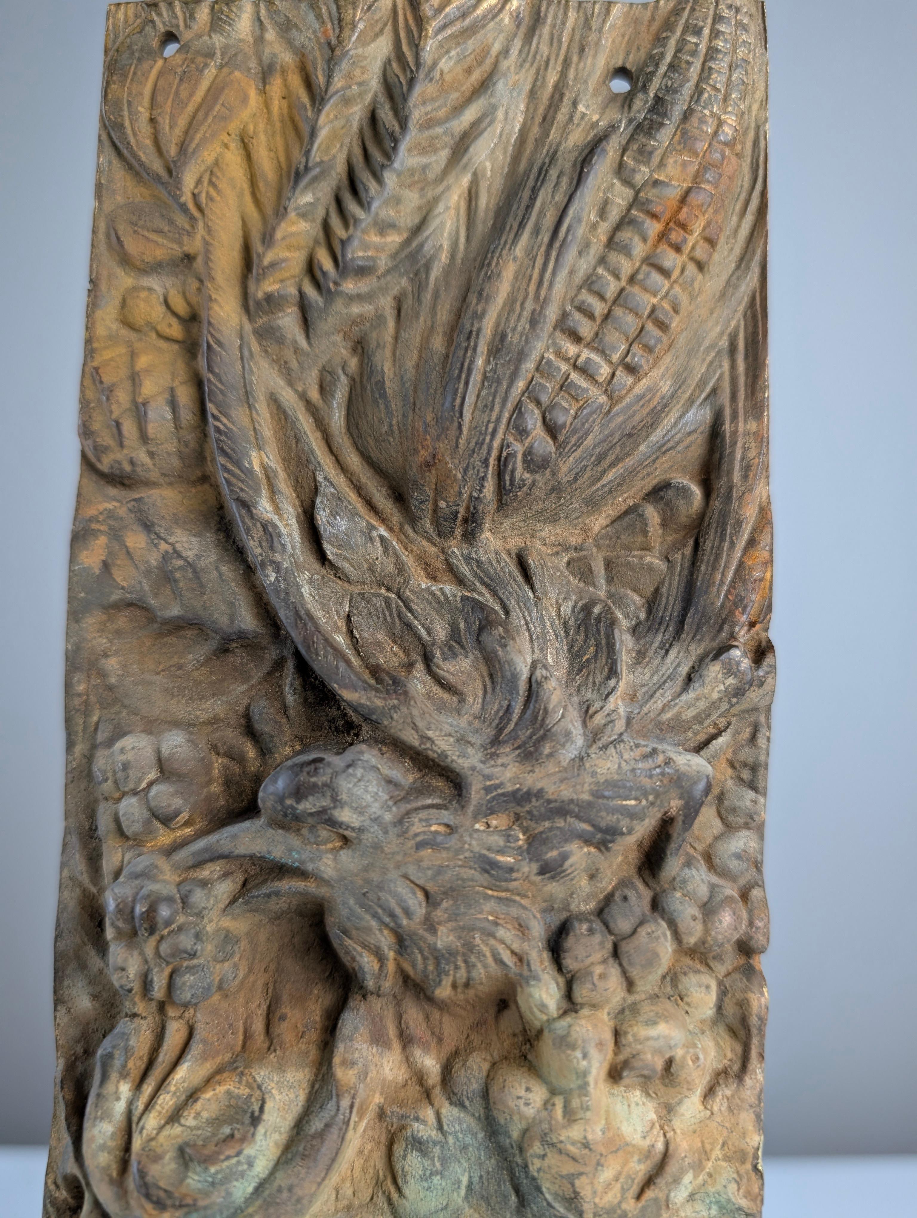 Bronze plaque sculpture with a finely detailed relief depicting a lush natural scene, where birds, flowers, and fruits intertwine masterfully. Created in the late 19th and early 20th centuries, its original patina, with bluish and orange tones,