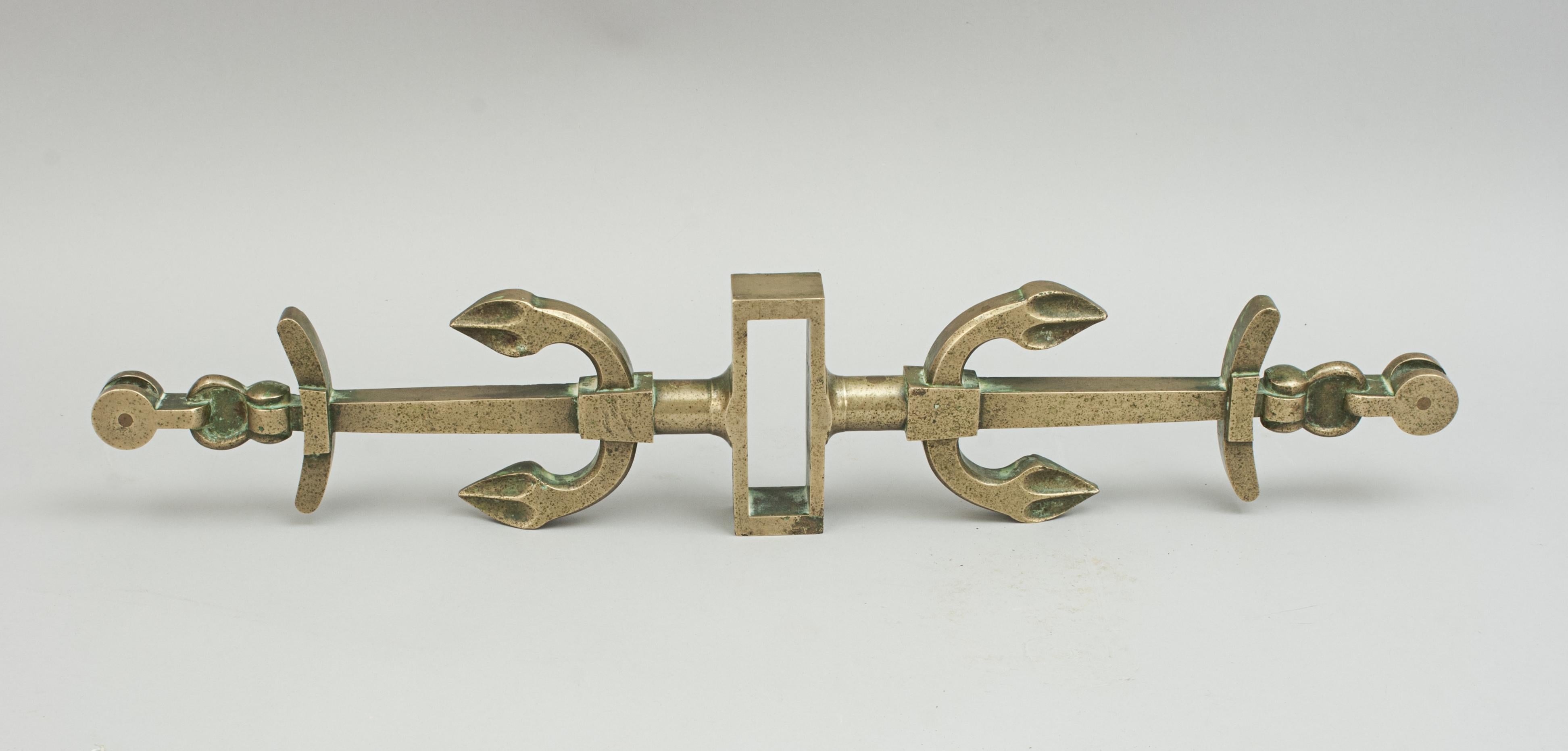 Bronze Tiller Yoke.
A late 19th century cast bronze rudder yoke with decorative detailing of two opposing anchors. It has a square opening for the rudder head and with single brass pulleys at the two ends. A nice decorative piece of maritime