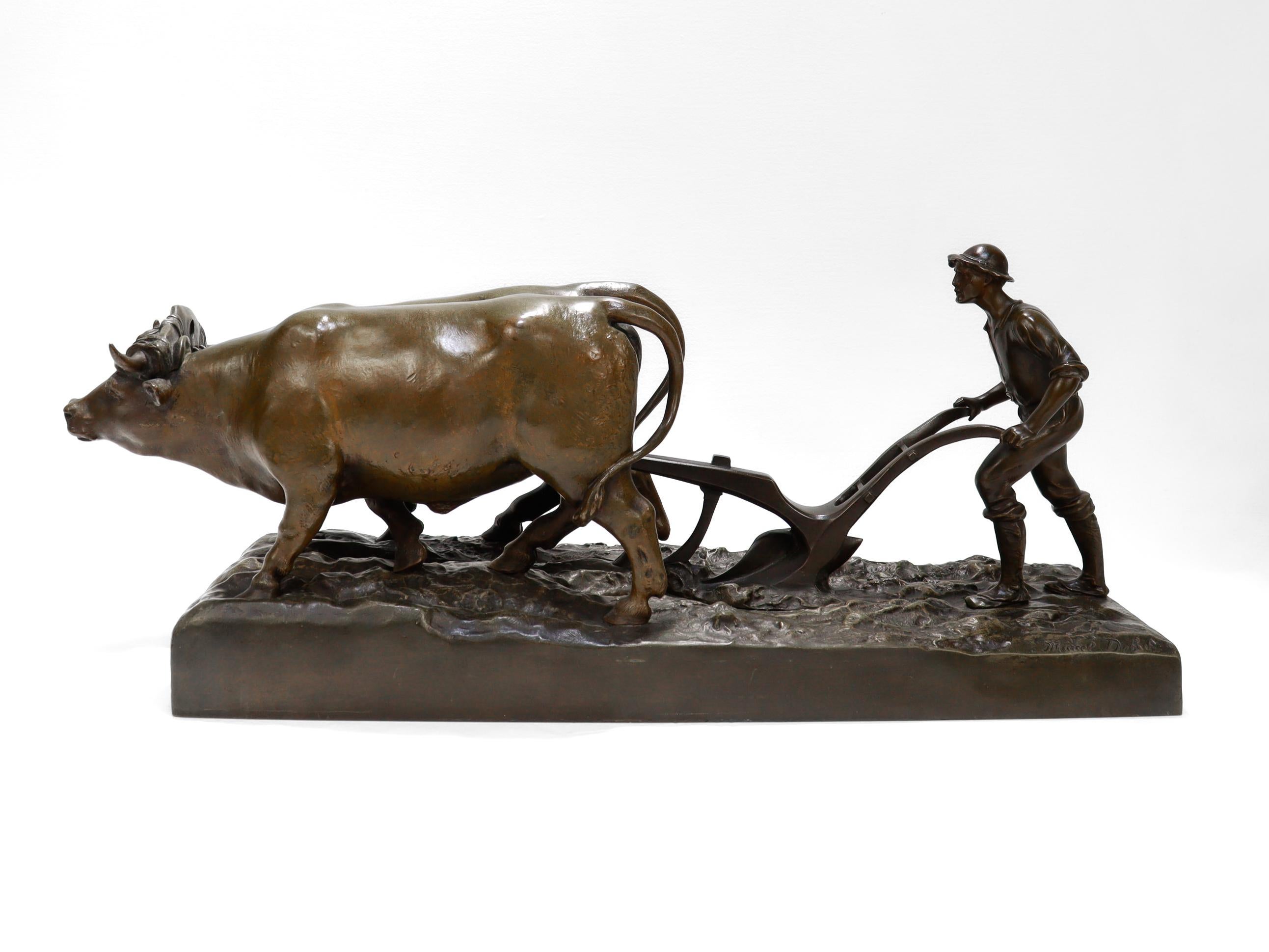 Une belle sculpture antique en bronze.

Par Marcel Debut (1865-1933).

En bronze patiné.

Sous la forme d'un fermier labourant un champ avec deux bœufs au sommet d'un socle de terrain en forme de terre boueuse.

Marqué pour Marcel Debut à