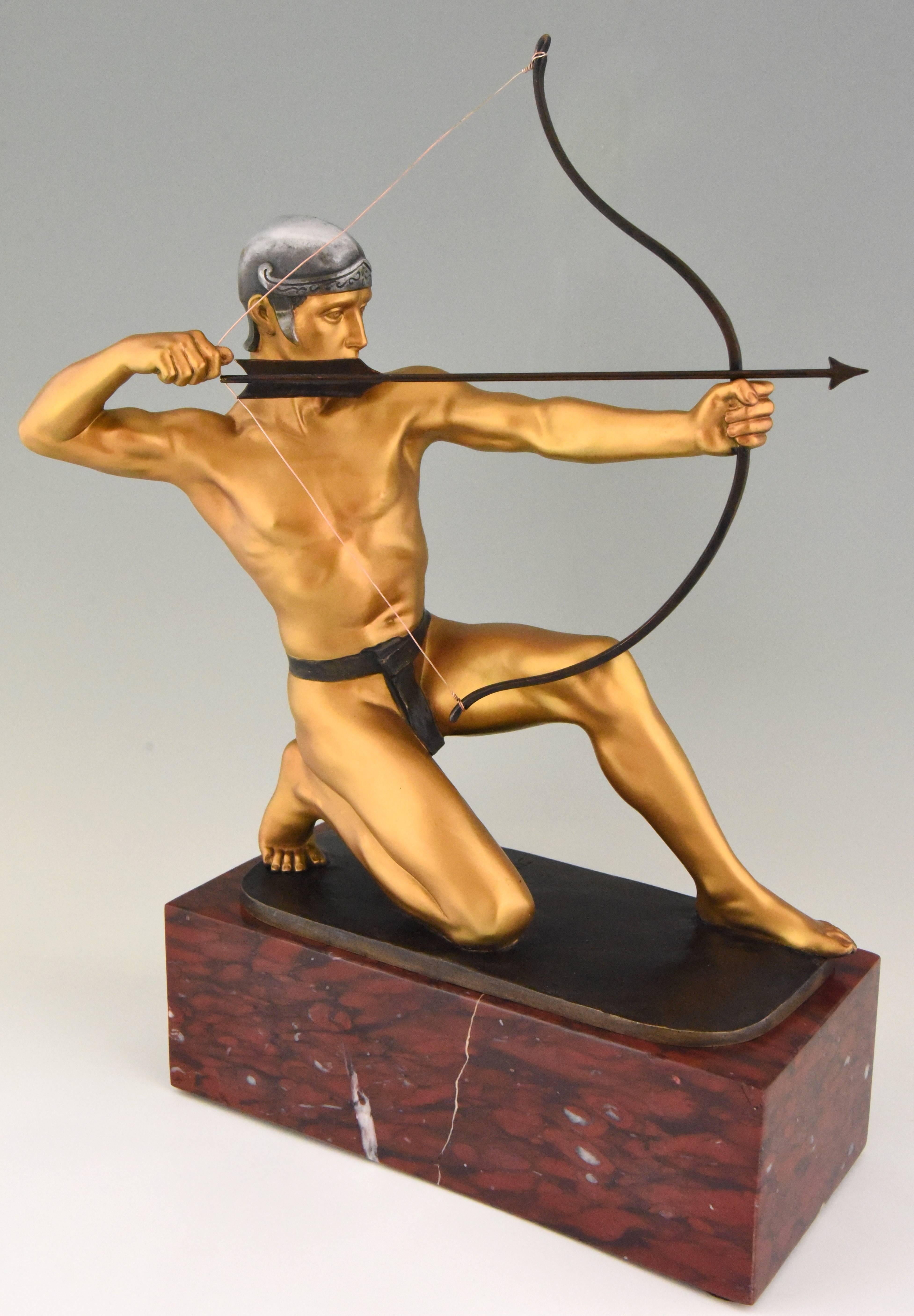 Antique bronze sculpture of an Archer with bow by the German sculptor Rudolf Kaesbach. The male nude is aiming in a kneeled pose and is wearing a silver helmet. 
The bronze has a multi-color patina and is mounted on a Belgian red marble base.
 