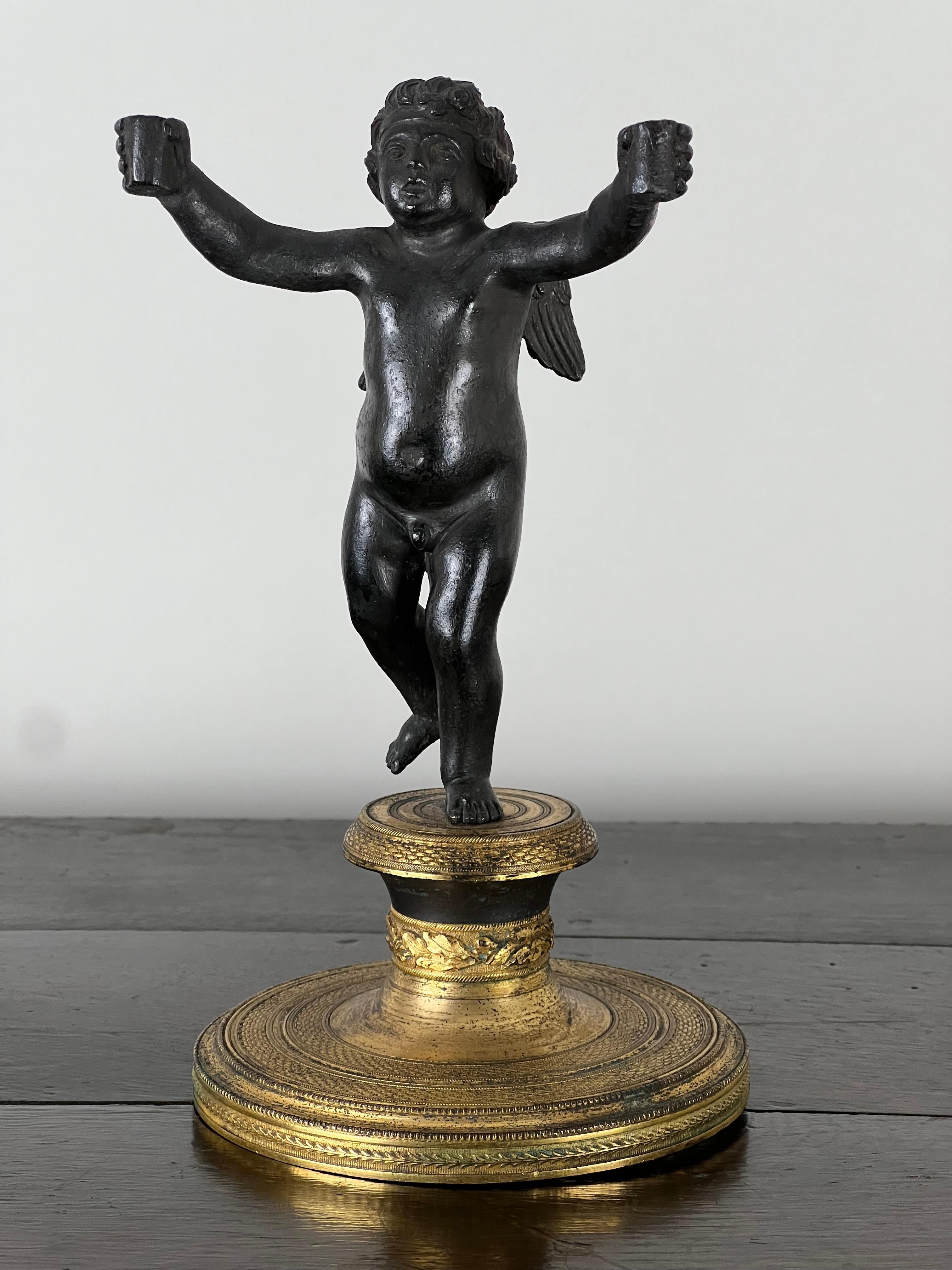 Questa scultura in bronzo antico di un putti che tiene in mano delle candele, attribuita all'artista francese Paul Edouard Delabrierre (1829-1912), cattura la natura giocosa e vivace del periodo romantico. Il pezzo ritrae un affascinante putto alato