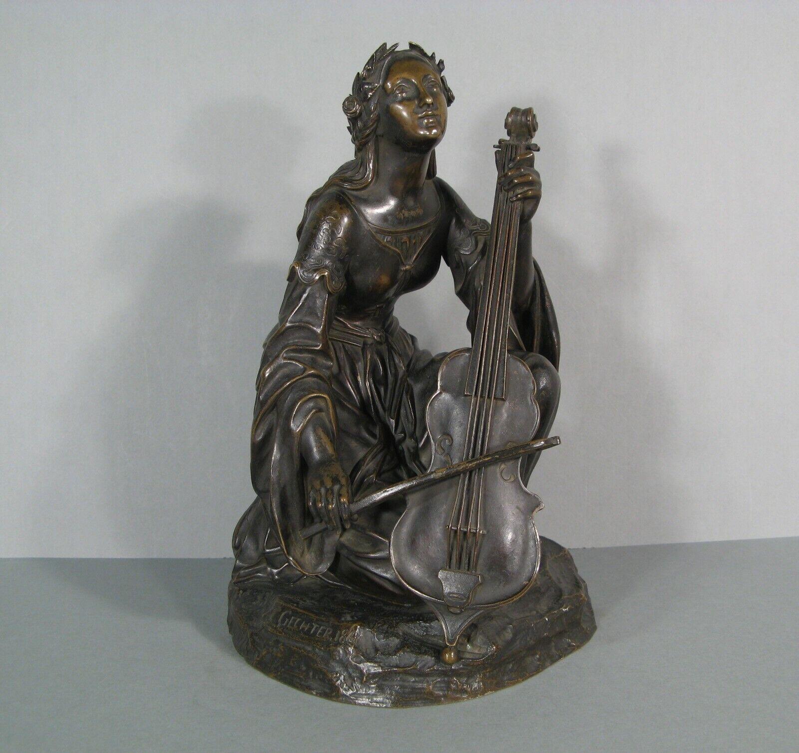 Esta exquisita escultura antigua de bronce de Jean-François Théodore Gechter (1795-1844) representa a una joven músico, probablemente Santa Cecilia, patrona de los músicos, tocando el violonchelo. Firmada y fechada 