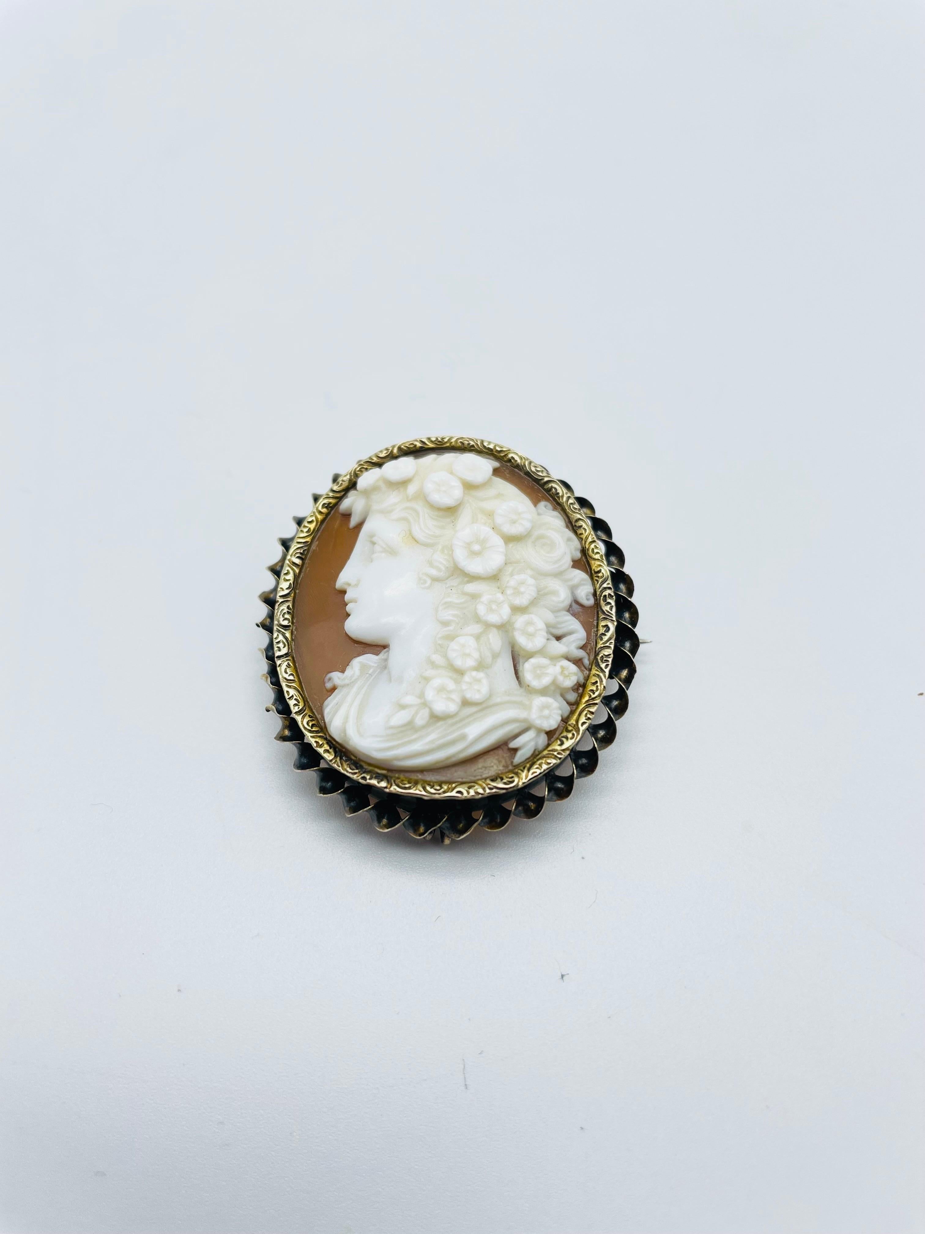 AThis antique brooch is a true work of art. Crafted in 14K yellow gold, it boasts a finely detailed cameo depicting the portrait of a young lady with flowing hair. The intricate craftsmanship is evident in every detail, from the delicate features of