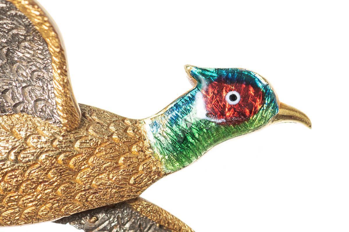 A finely modelled and heavy quality antique brooch of a cock pheasant in flight in two colour gold with an enamelled head. The body is in 18 carat yellow gold with the underside of the wings in 15 carat white gold. The workmanship in the