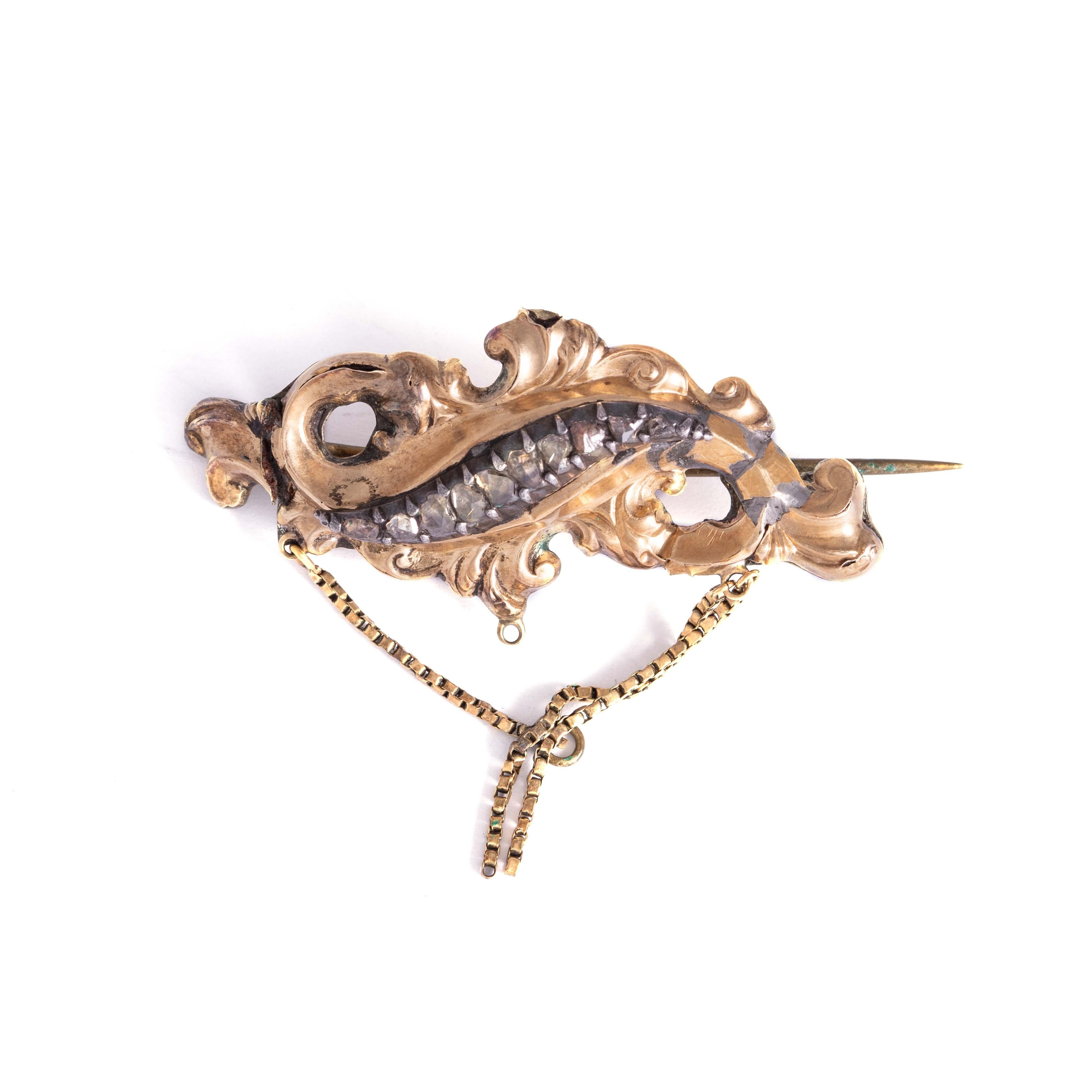 14K gold and silver brooch set by rose-cut diamonds.
Dimensions (without chain): 4.50 centimeters x 2.00 centimeters. 
Gross weight: 4.64 grams.