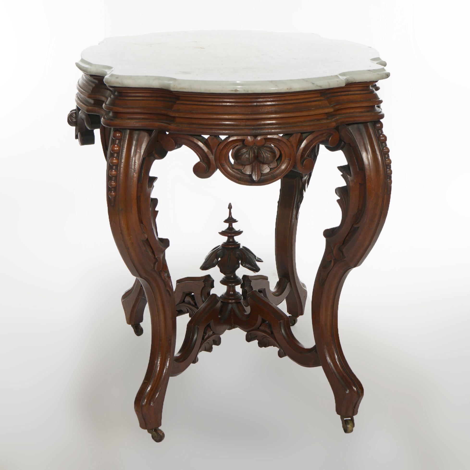An antique Renaissance Revival Brooks Brothers turtle top parlor table offers beveled and shaped marble top over walnut base having carved skirt with central nut still life, raised on cabriole legs with beaded knees and stylized scroll form