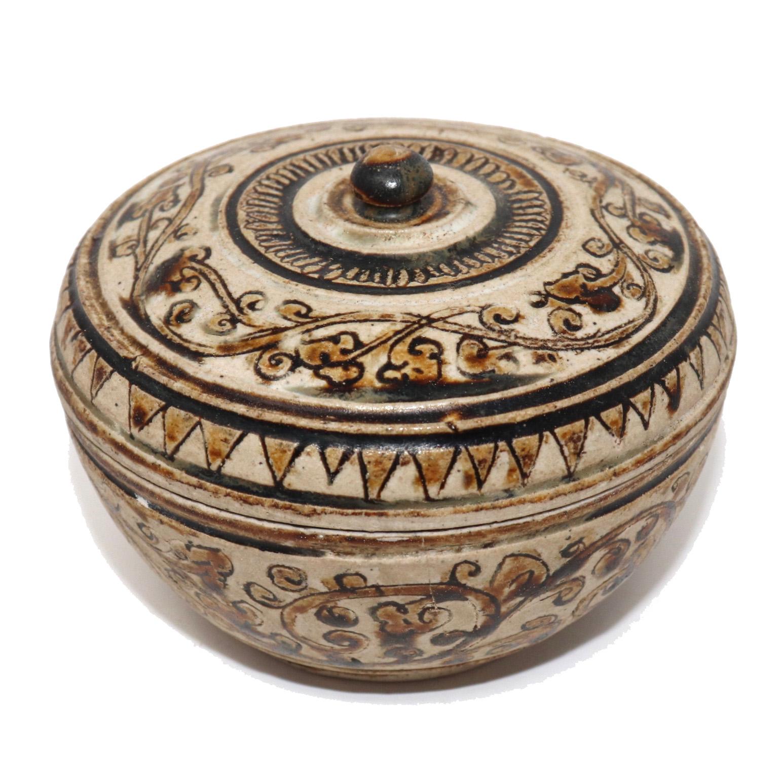 Antique ceramic condiment box from the Sawankhalok kilns, Thailand of shouldered globular form with a domed top having a serrated petal ring around a raised button finial the domed portion with continuous foliate vine design decorated in a