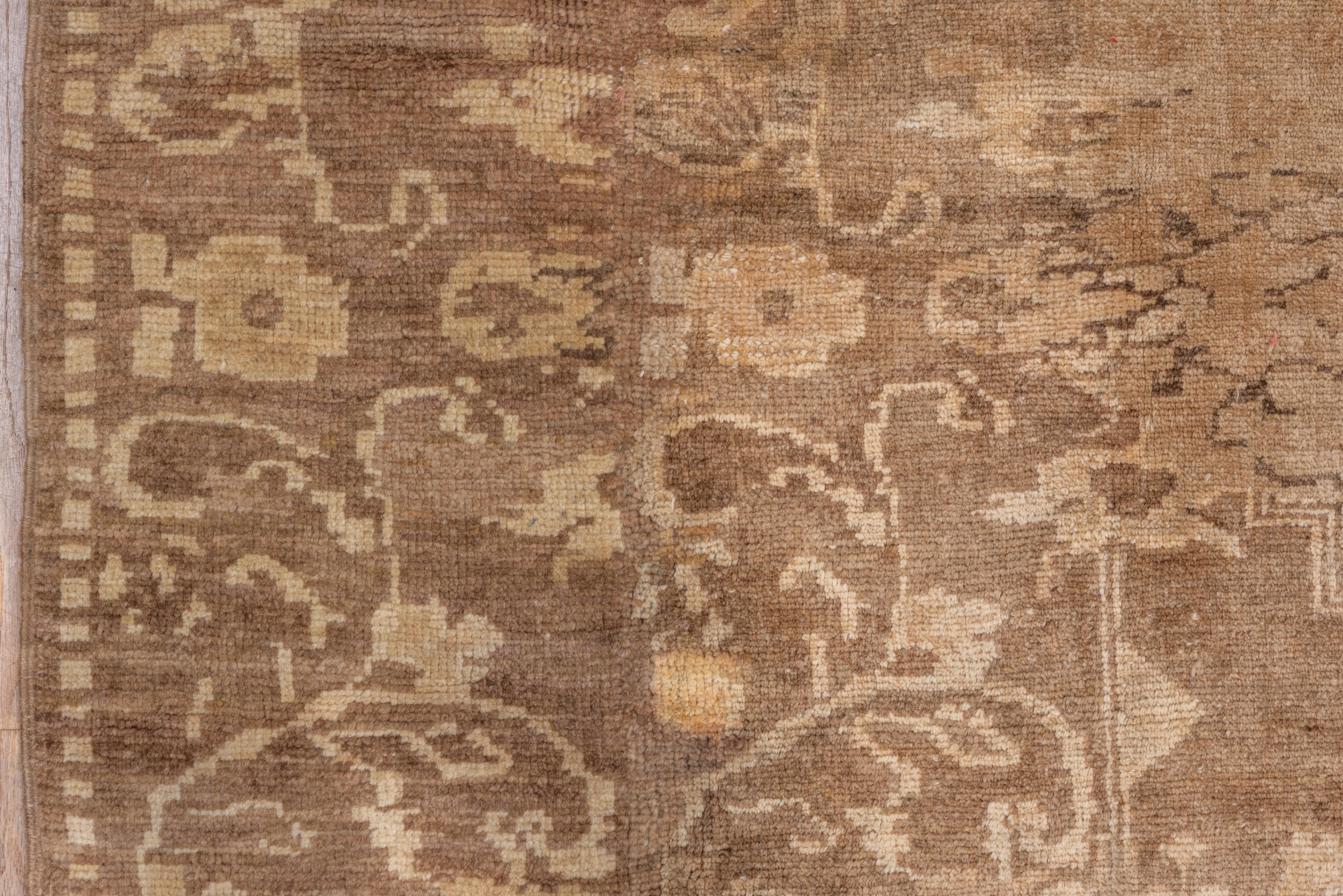 The light brownish field of this West Anatolian town carpet shows a widely stepped and pendanted brown medallion, with similar semi-geometric corners. Doubled main border of floral sprays on brown and gold grounds.