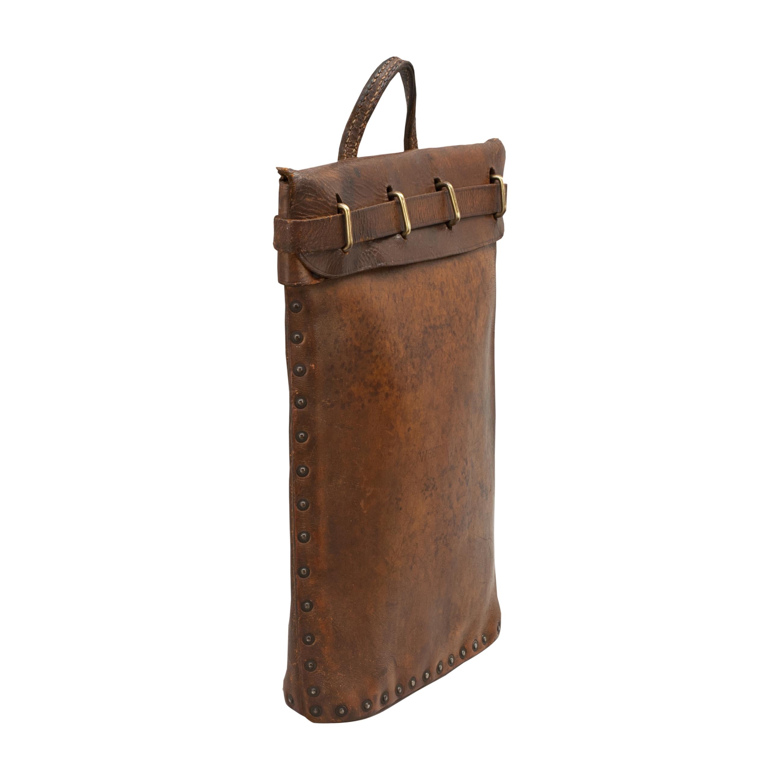 Vintage leather mailbag, briefcase.
A sturdy brown leather bag with one central carry handle and riveted seams. It has a leather belt front closure which feeds through brass metal loops to create a secure closing and is finished with a metal clip