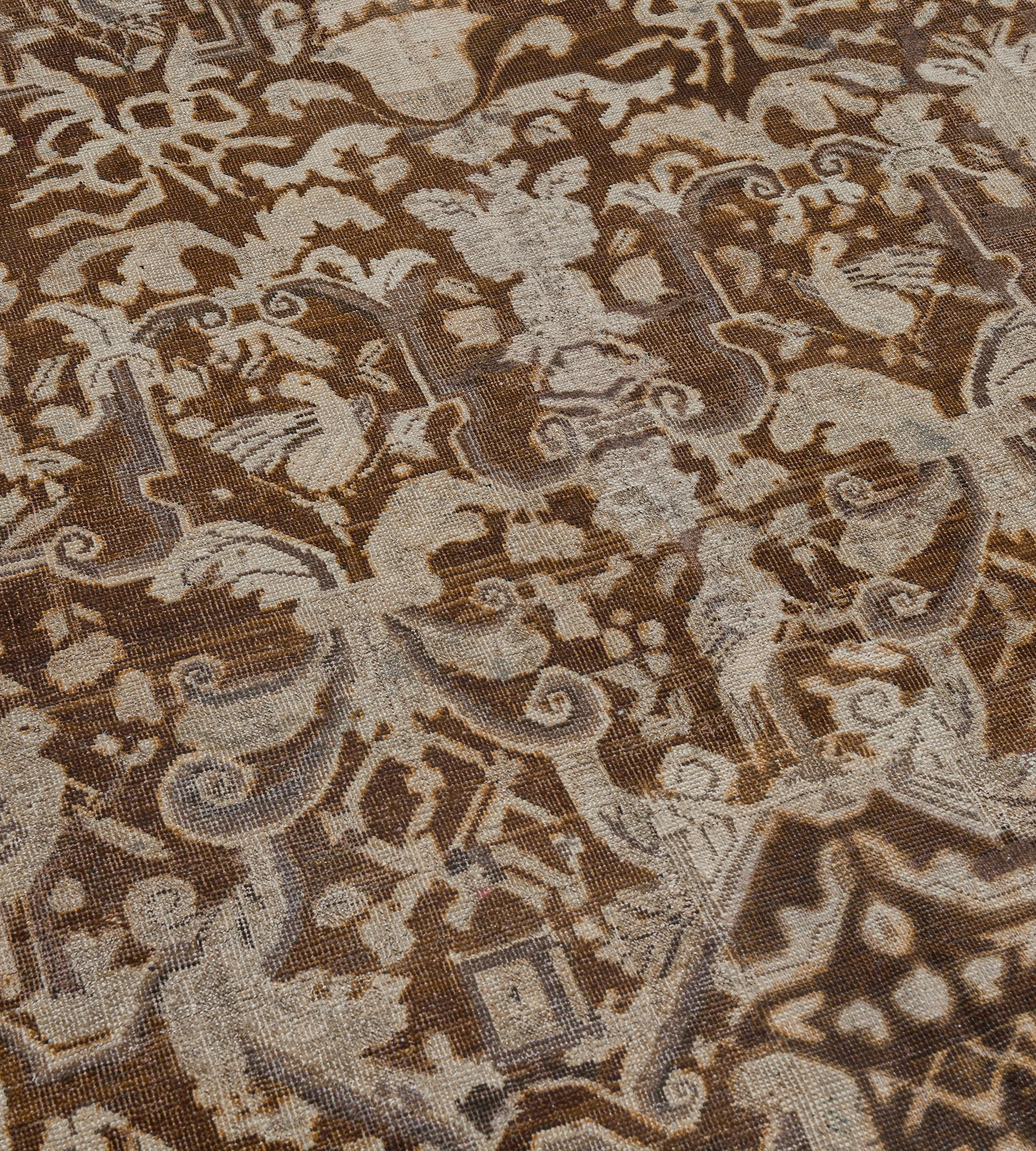 Esta antigua alfombra de Karabagh tiene un campo marrón tabaco con un diseño general de hileras horizontales de atrevidas guirnaldas enlazadas de marfil y marrón topo, junto con hojas de acanto atadas que forman cartuchos, cada uno de ellos con un