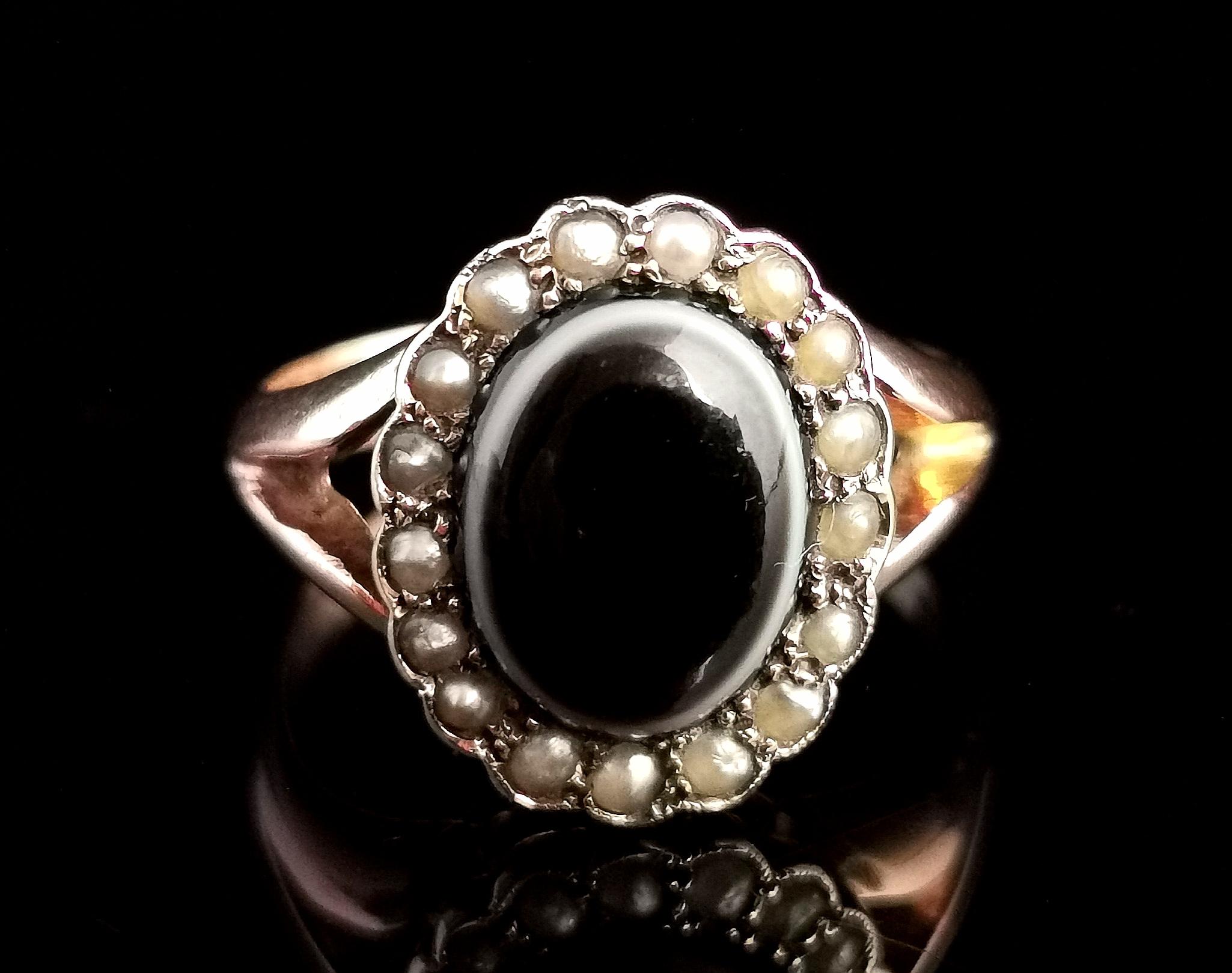 A beautiful antique early Art Deco era mourning ring

It features a central oval bullseye agate cabochon in Black with white and brown banding surrounded by a halo of creamy seed pearls.

It has chunky smooth polished band with a slight D