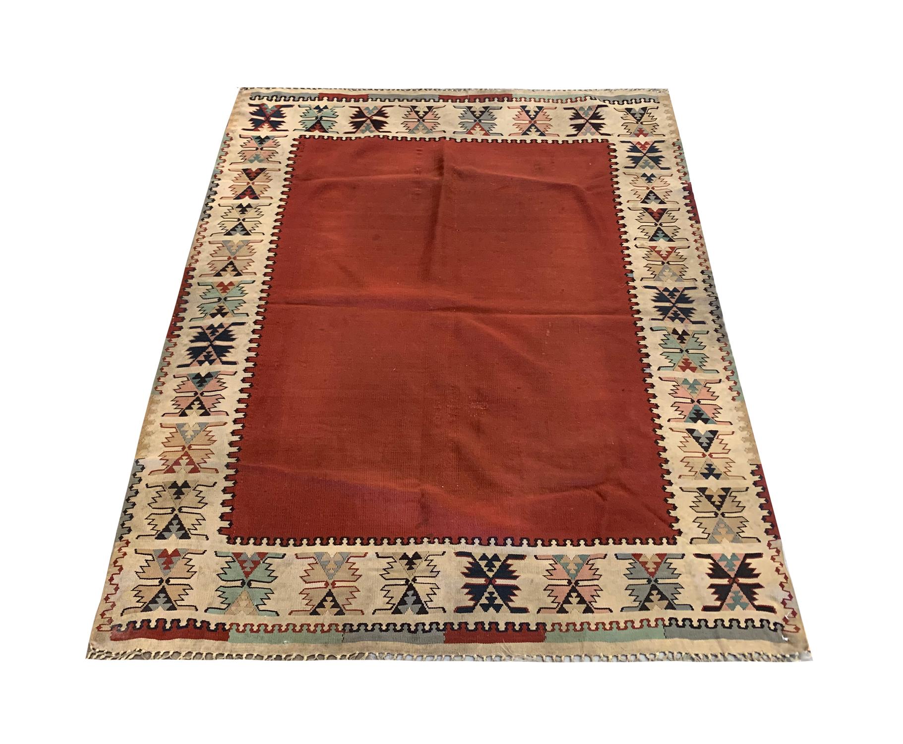 Ce Rug & Kilim bourgogne ancien, datant du début des années 1900, est un exceptionnel tissage plat en laine réalisé à la main qui incarne la beauté minimaliste de l'artisanat tribal traditionnel. Doté d'un riche champ rouge bordeaux encadré d'une