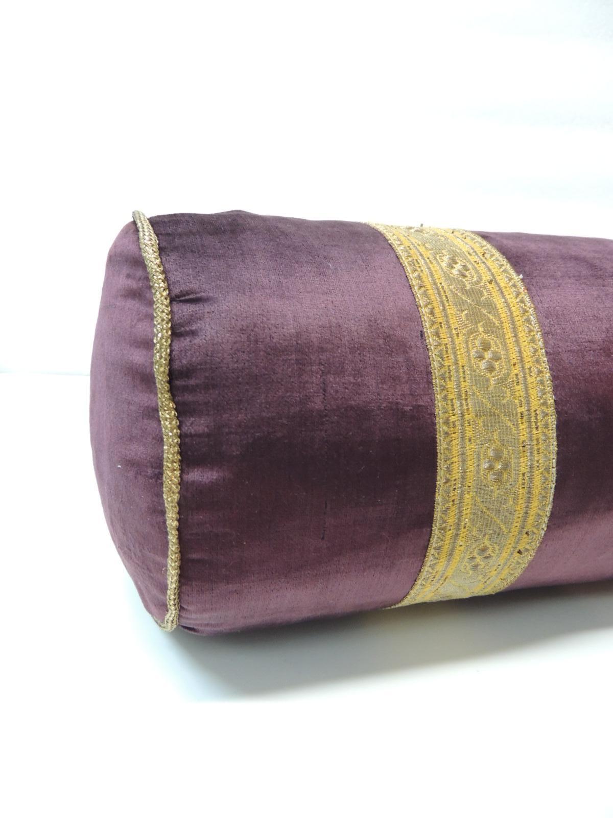 Antique burgundy silk velvet round bolster handmade pillow with gold metallic trims.
Burgundy antique silk bolster decorative pillow designed with two parallel bands of
 antique gold metallic trims and metallic rope details on both edges
handmade in