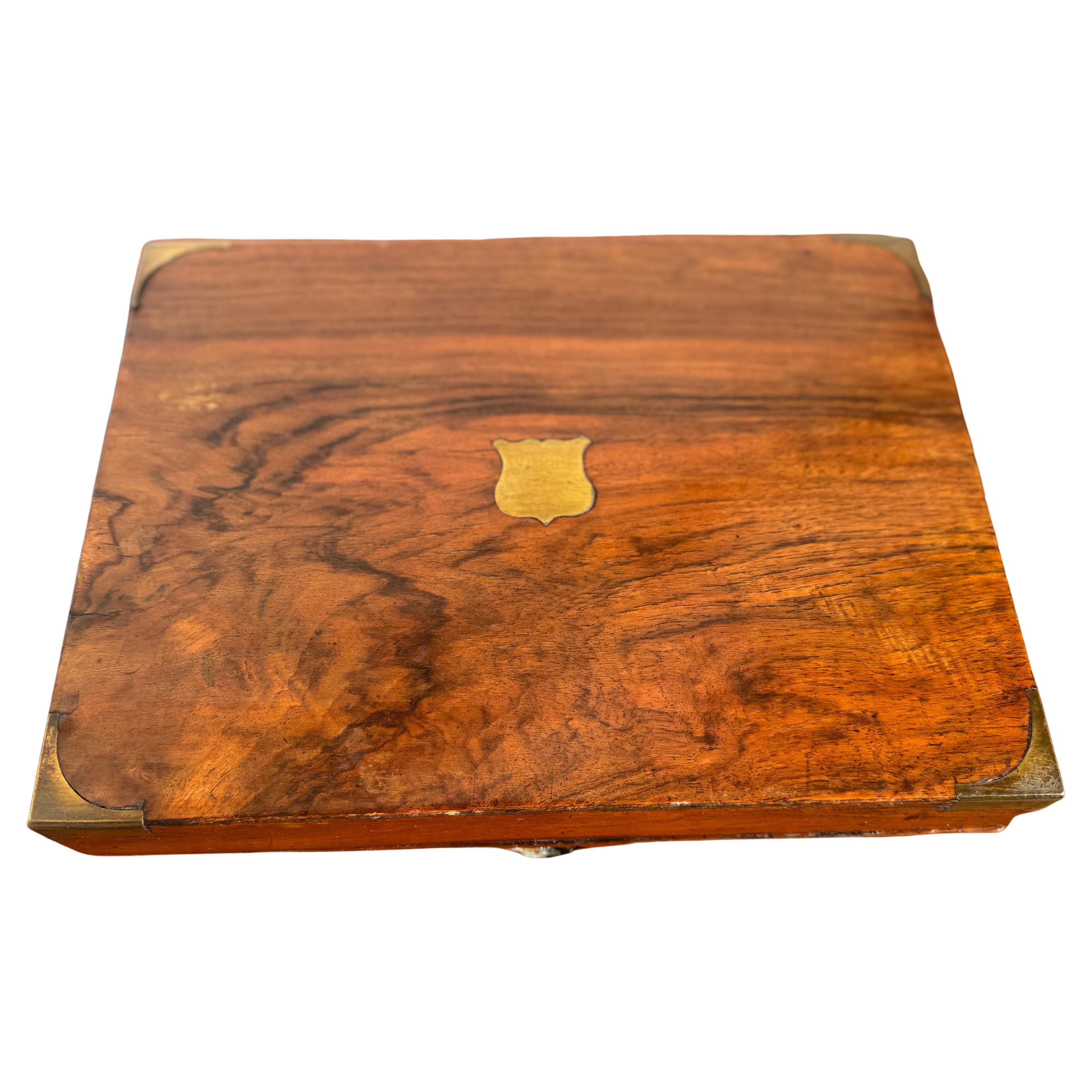 Questo è un lavoro fantastico. È costruito in radica di noce.
Presenta degli angoli in ottone e un medaglione in ottone sulla parte superiore.
Si apre rivelando una superficie di scrittura e un posto per i pozzetti d'inchiostro e le penne.
Il