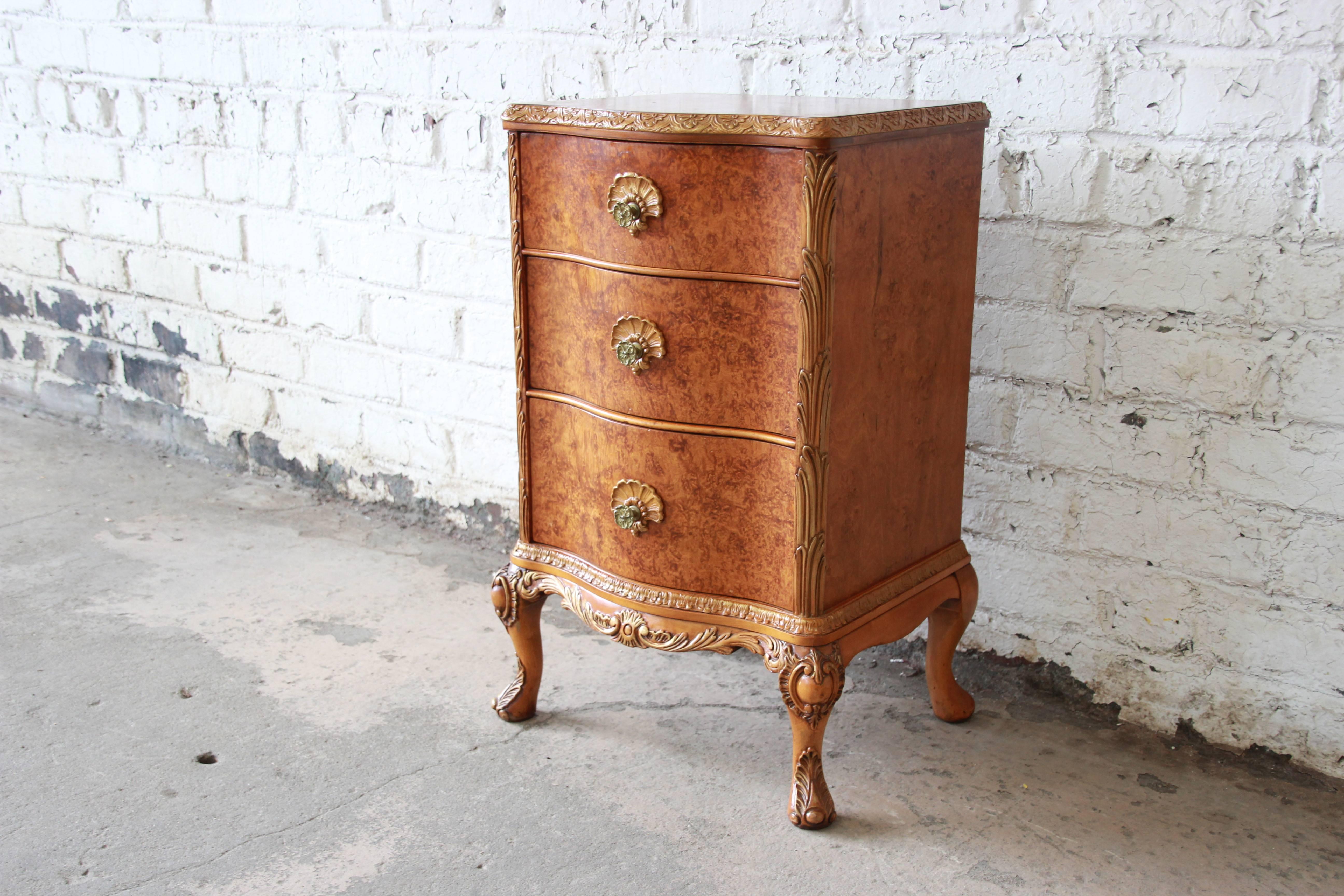 Offering a beautiful burled maple nightstand by Romweber. The nightstand offer three large drawers with original pulls and floral designed accents. It has carved French details throughout the piece and is a stunning piece for any room. The piece is