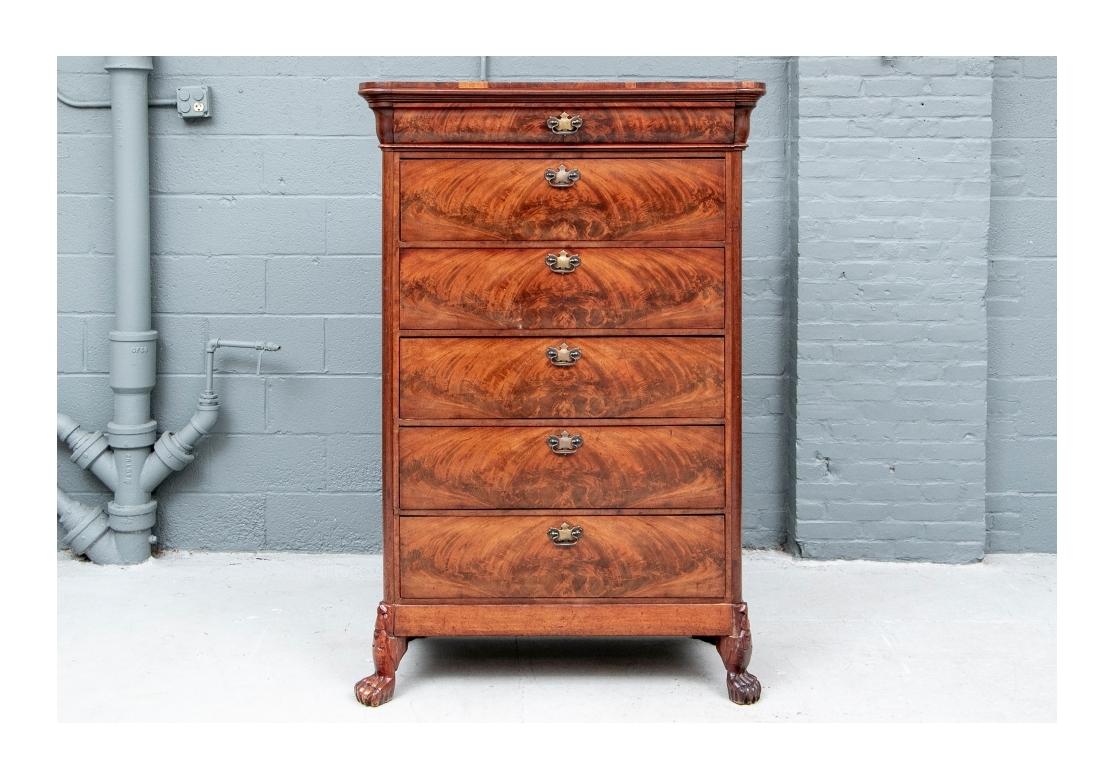 A tall cabinet with carved cavetto cornice, over a slim curved frieze drawer and one upper and two lower long drawers. The middle faux drawers drop down to the secretary. The fitted interior with drawers, and a center compartment with door housing